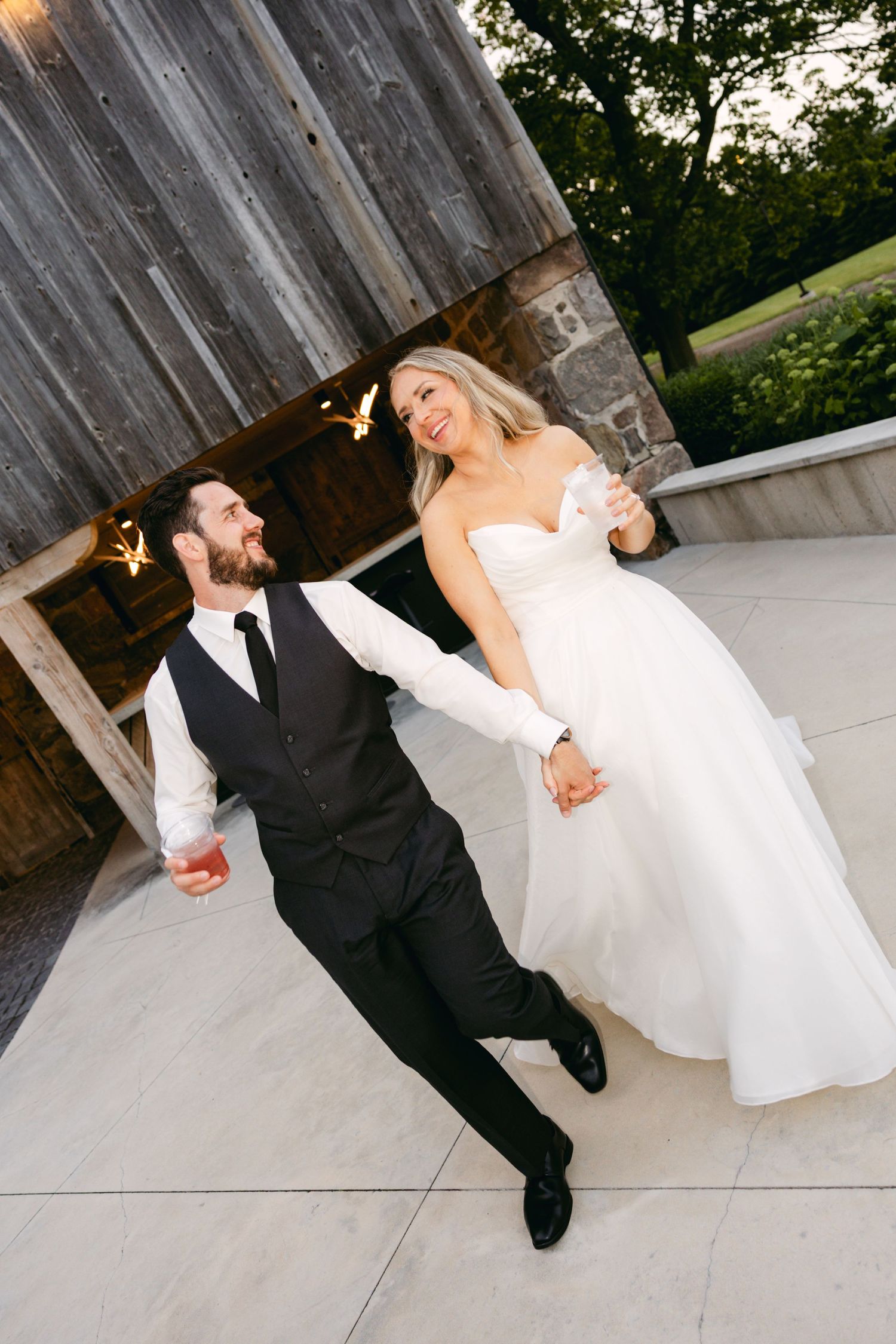 Couple shares romantic moments against a rustic barn wall during their wedding reception.