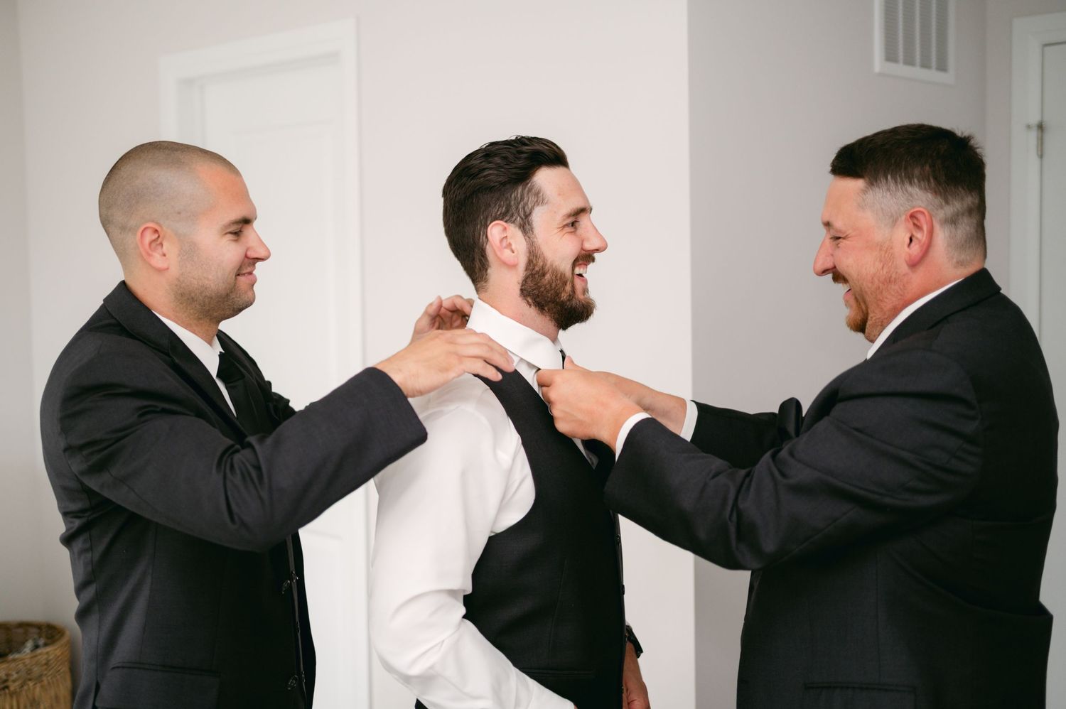 Groomsmen help adjust the groom's tie before the wedding ceremony.