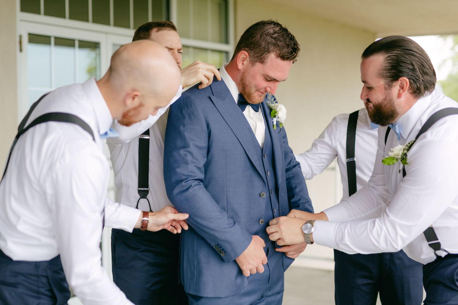 Wedding party members in formal attire and suspenders preparing for ceremony.