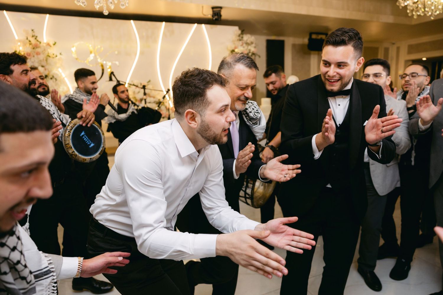 Guests engage in animated celebration during a lively wedding reception in an elegant venue.