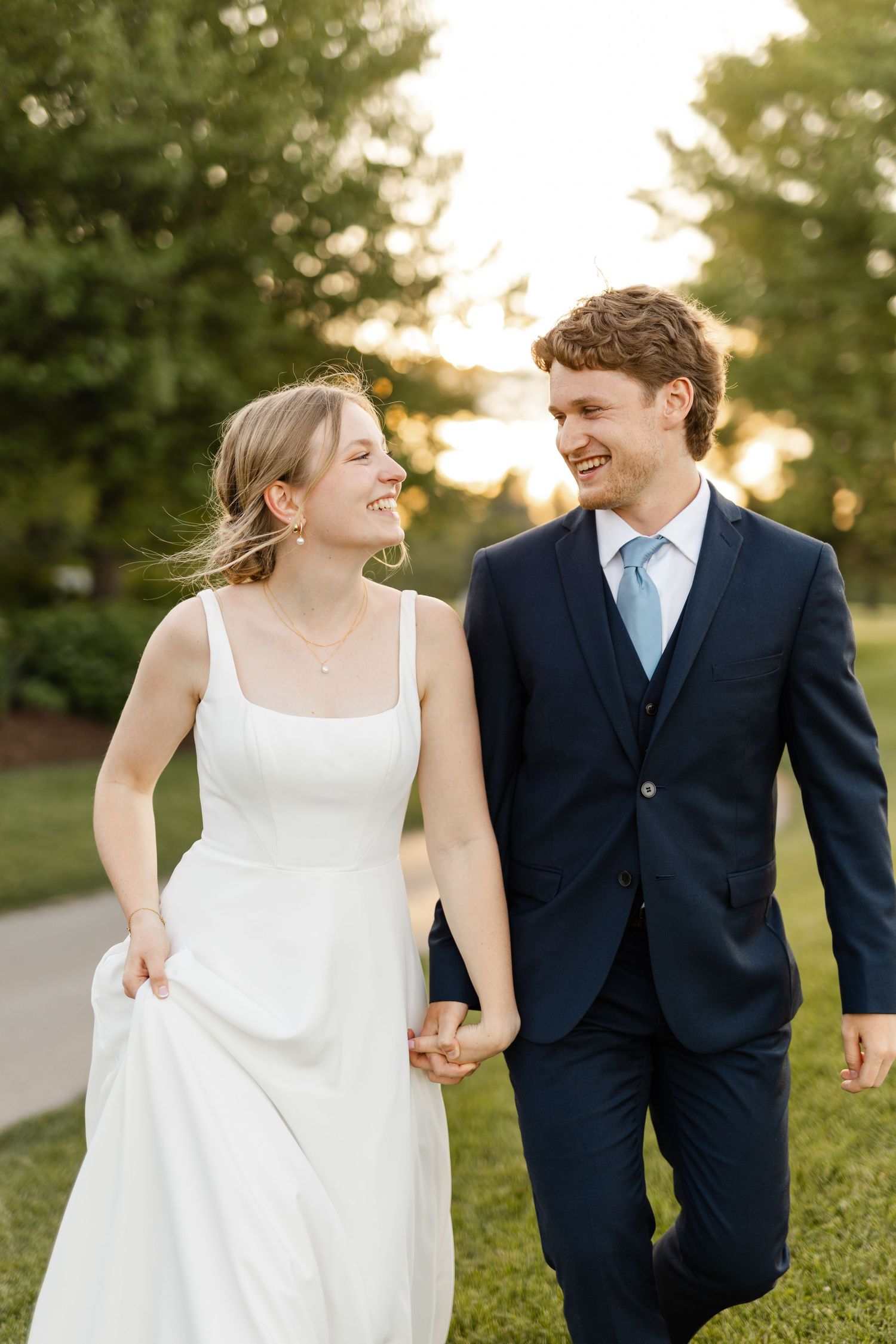 A candid wedding photo captures the couple laughing together in golden evening light.
