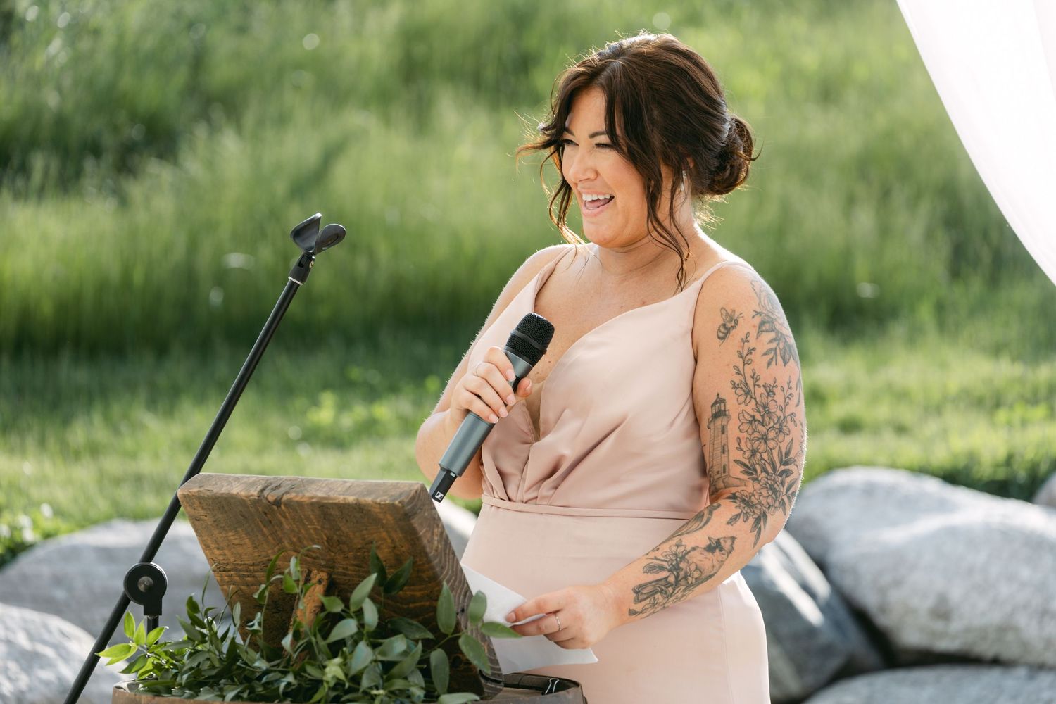 Wedding singer in blush dress performs during outdoor celebration.