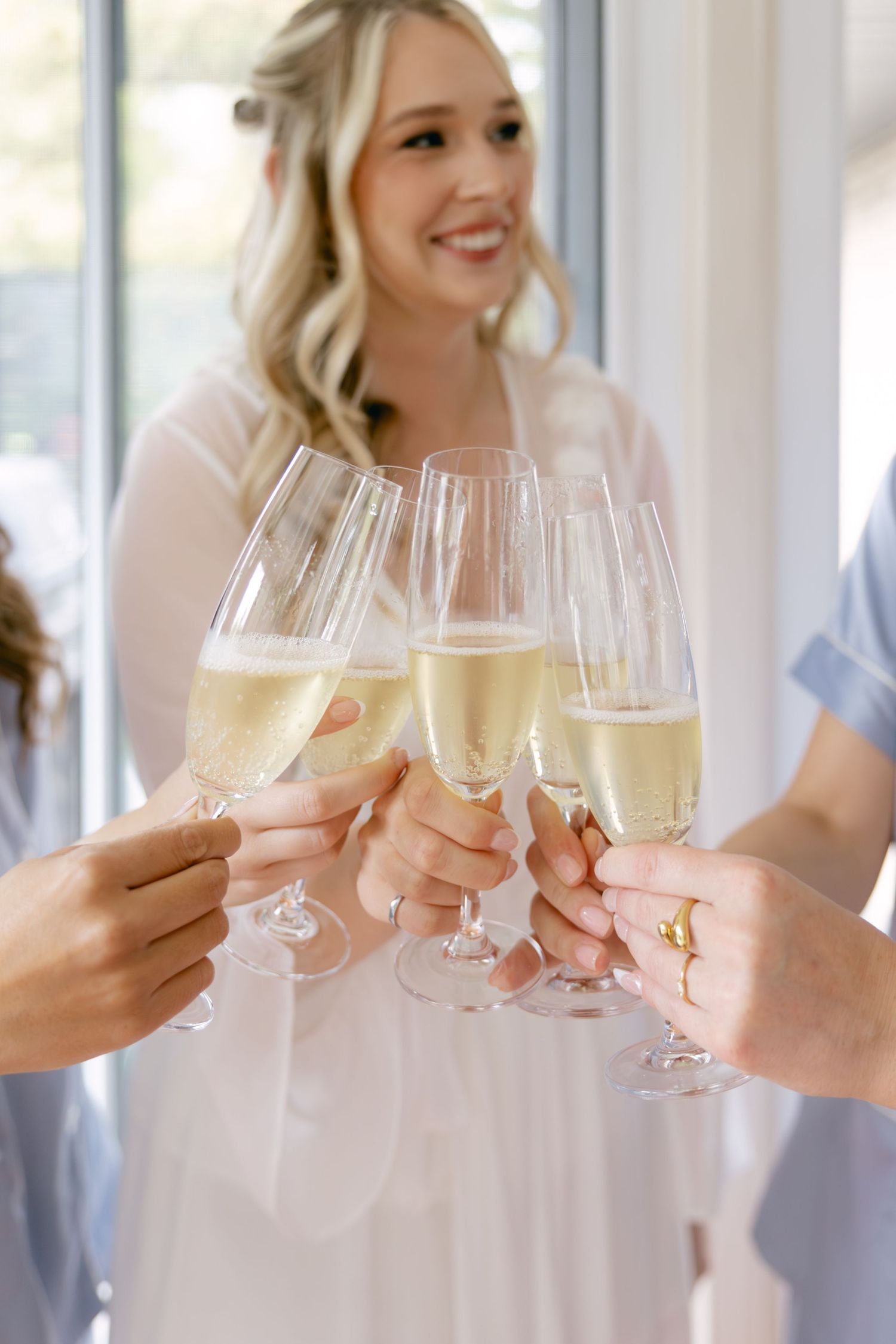 Hands raise champagne glasses in a celebratory toast at an elegant indoor gathering.