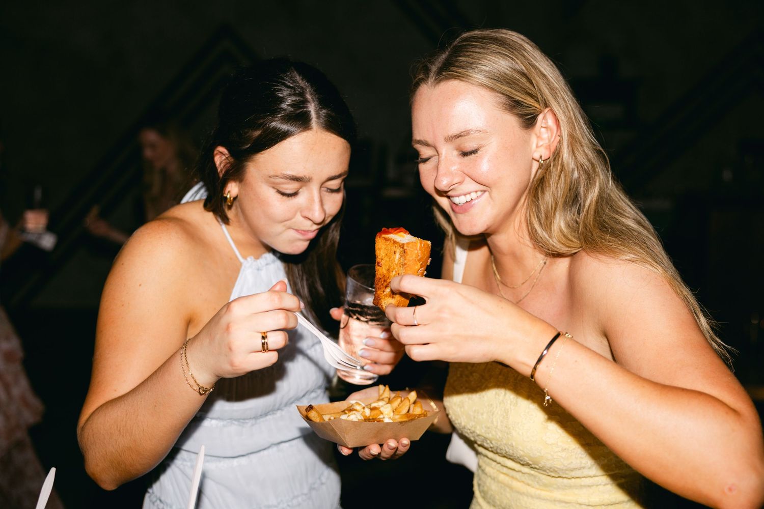 Wedding guests sharing drinks and laughing during reception celebration.