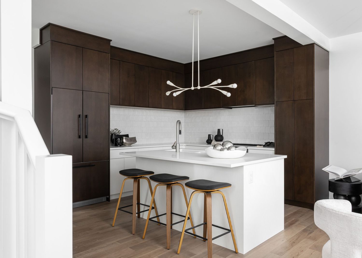 Open concept kitchen with contrasting dark and white elements featuring modern pendant lights.