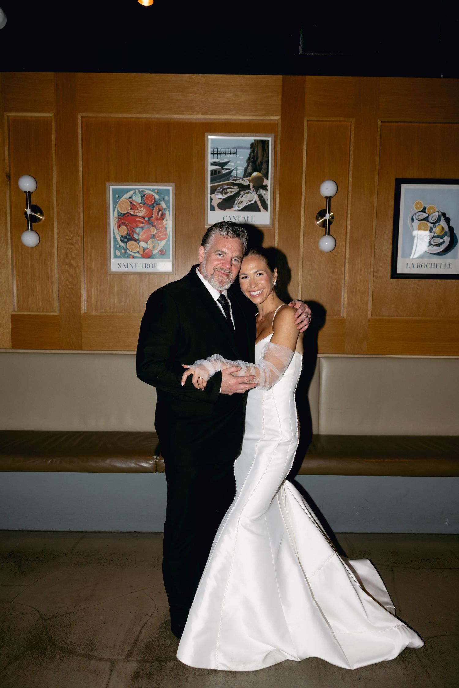 Bride and older gentleman in black suit share a dance at elegant wedding reception venue.