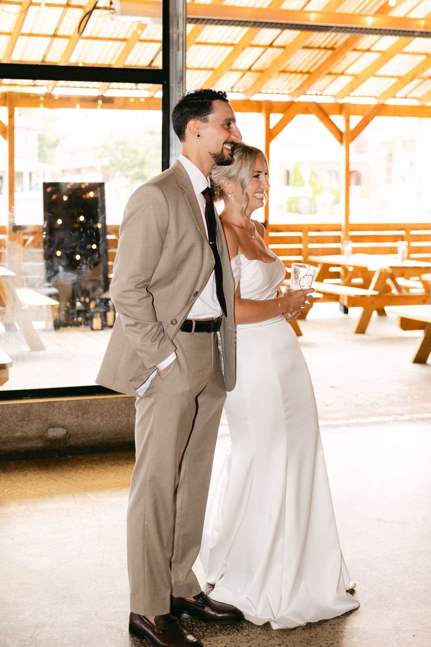 Wedding celebration moments captured in a covered outdoor venue with tan and white attire.
