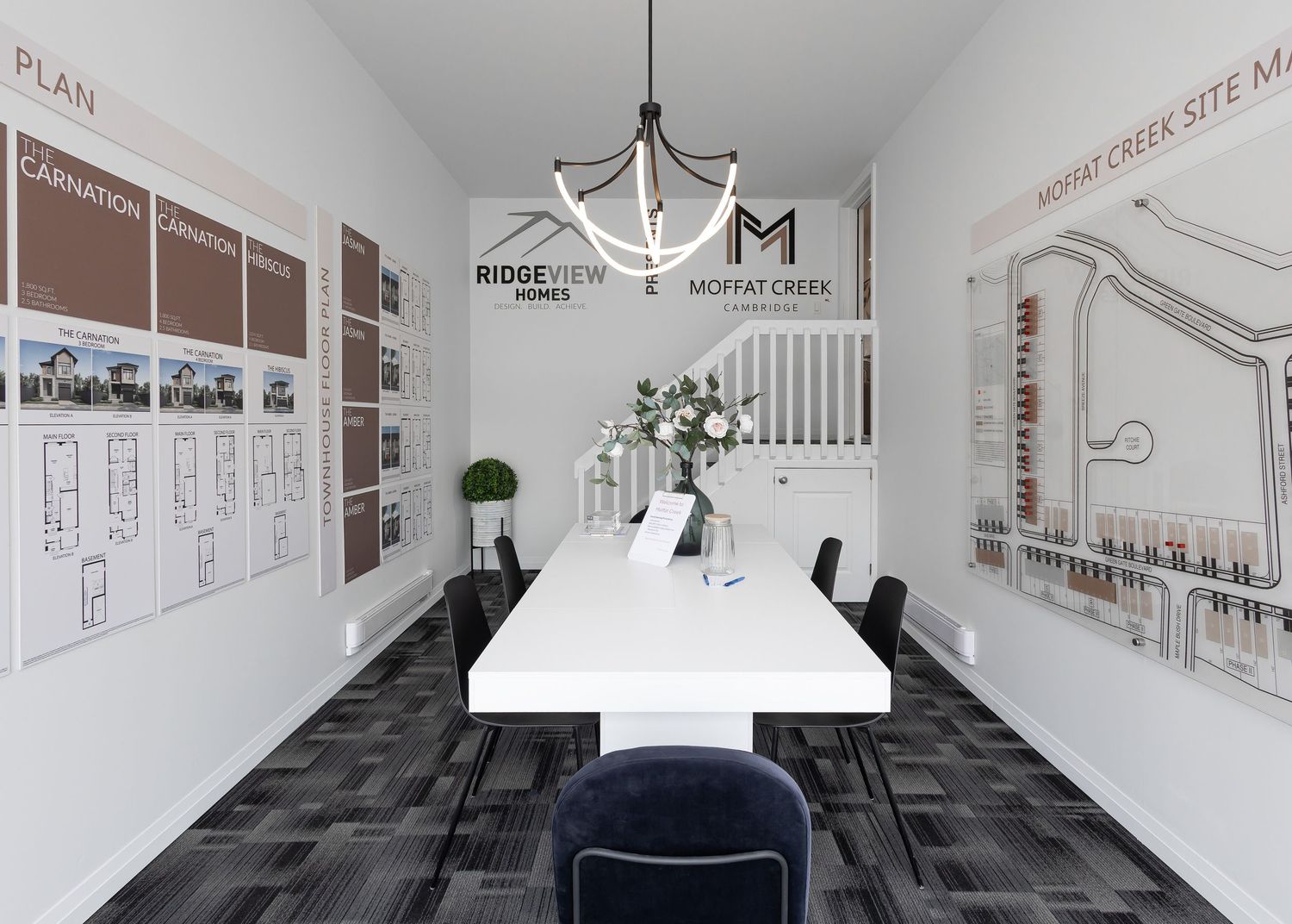 Office hallway with architectural drawings and floor plans displayed on white walls.