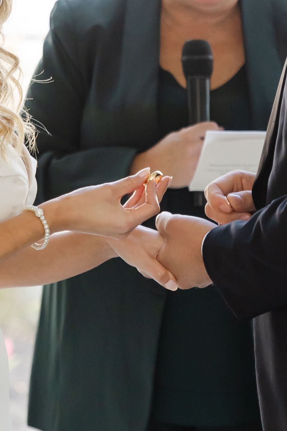 Close-up of hands exchanging rings during wedding ceremony.