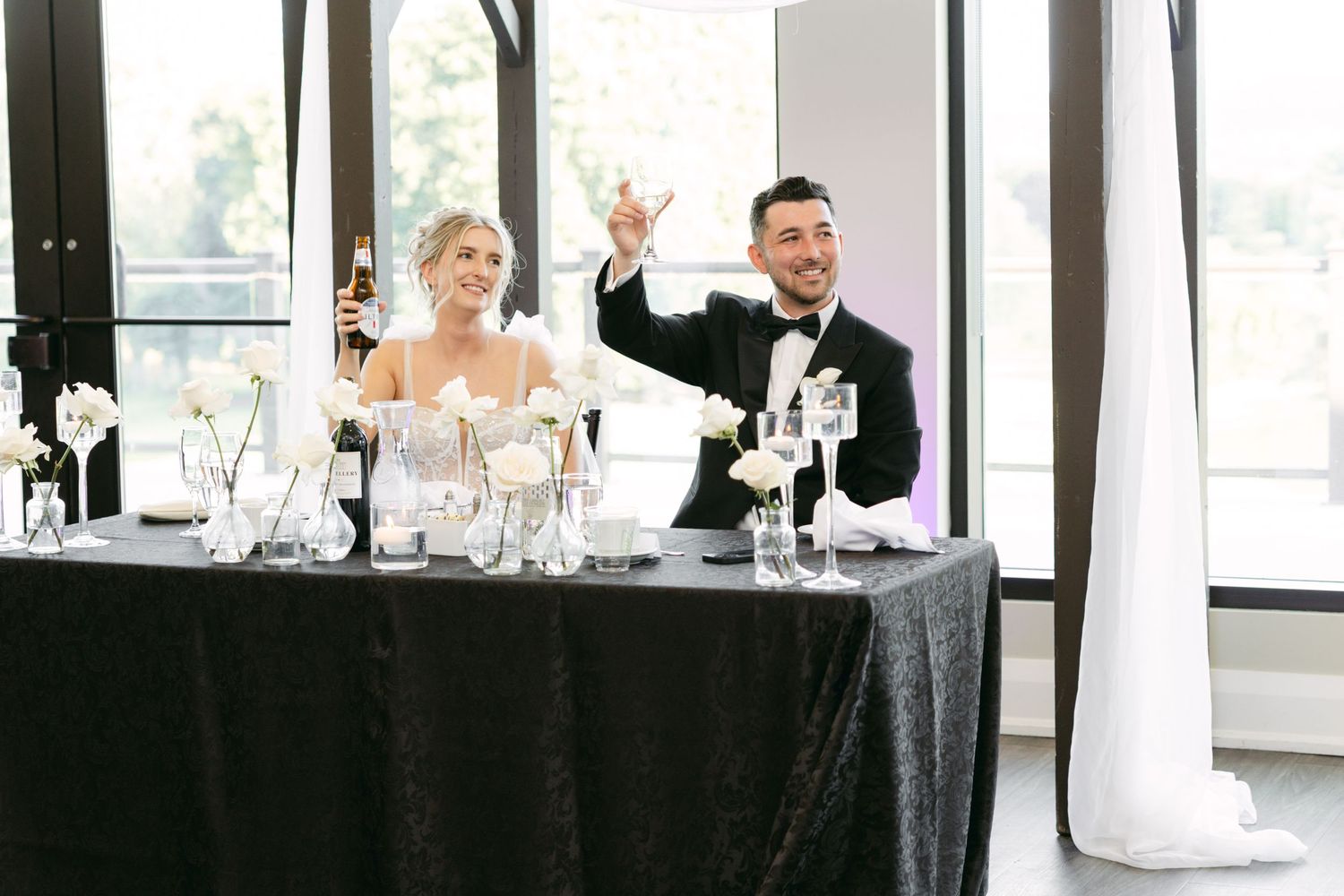 Modern wedding reception setup with white decor and large windows in an elegant venue.