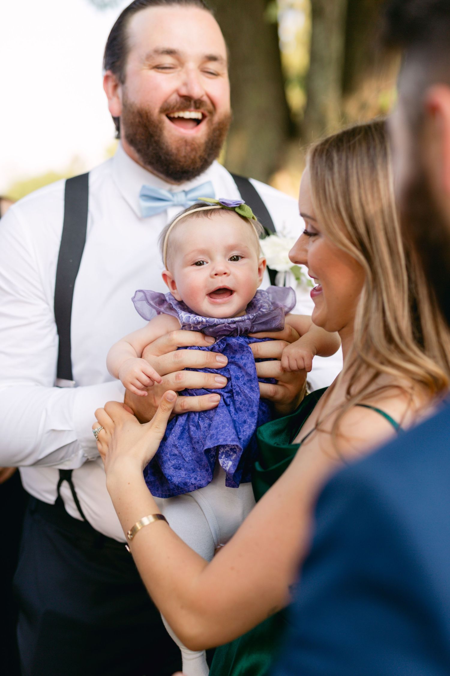 Happy moment shared with baby in purple dress at outdoor celebration.