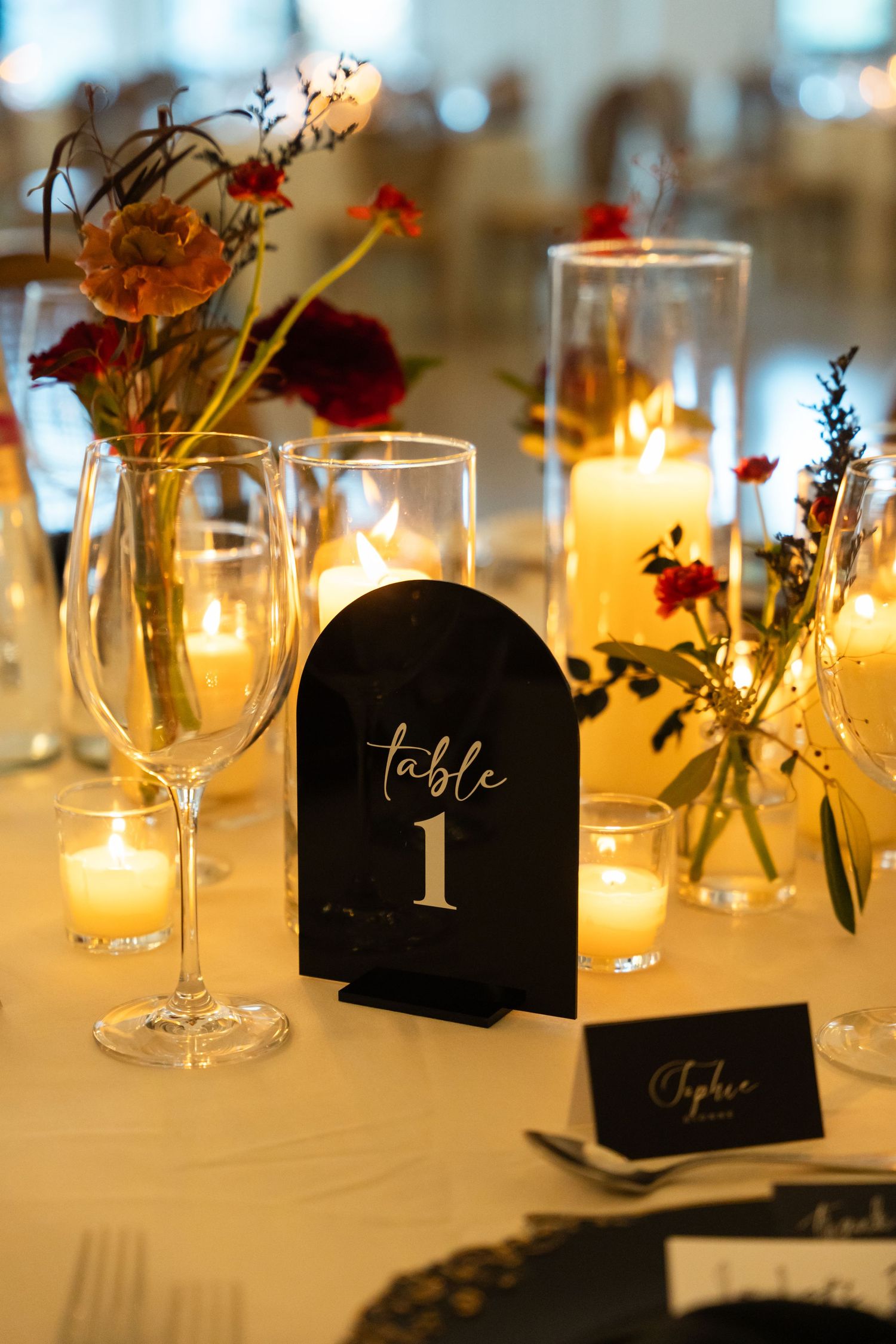 Elegant table settings with candlelight and black table numbers for wedding reception.