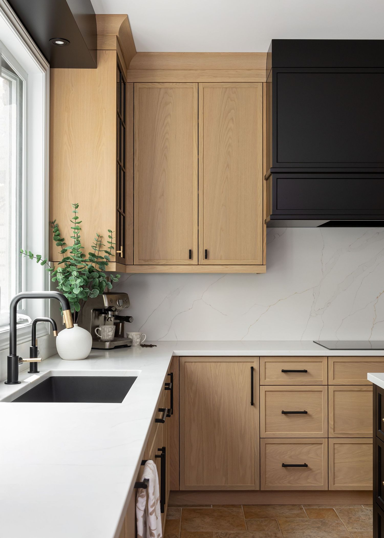Minimalist kitchen with white countertops and light wood shaker cabinets in natural lighting.