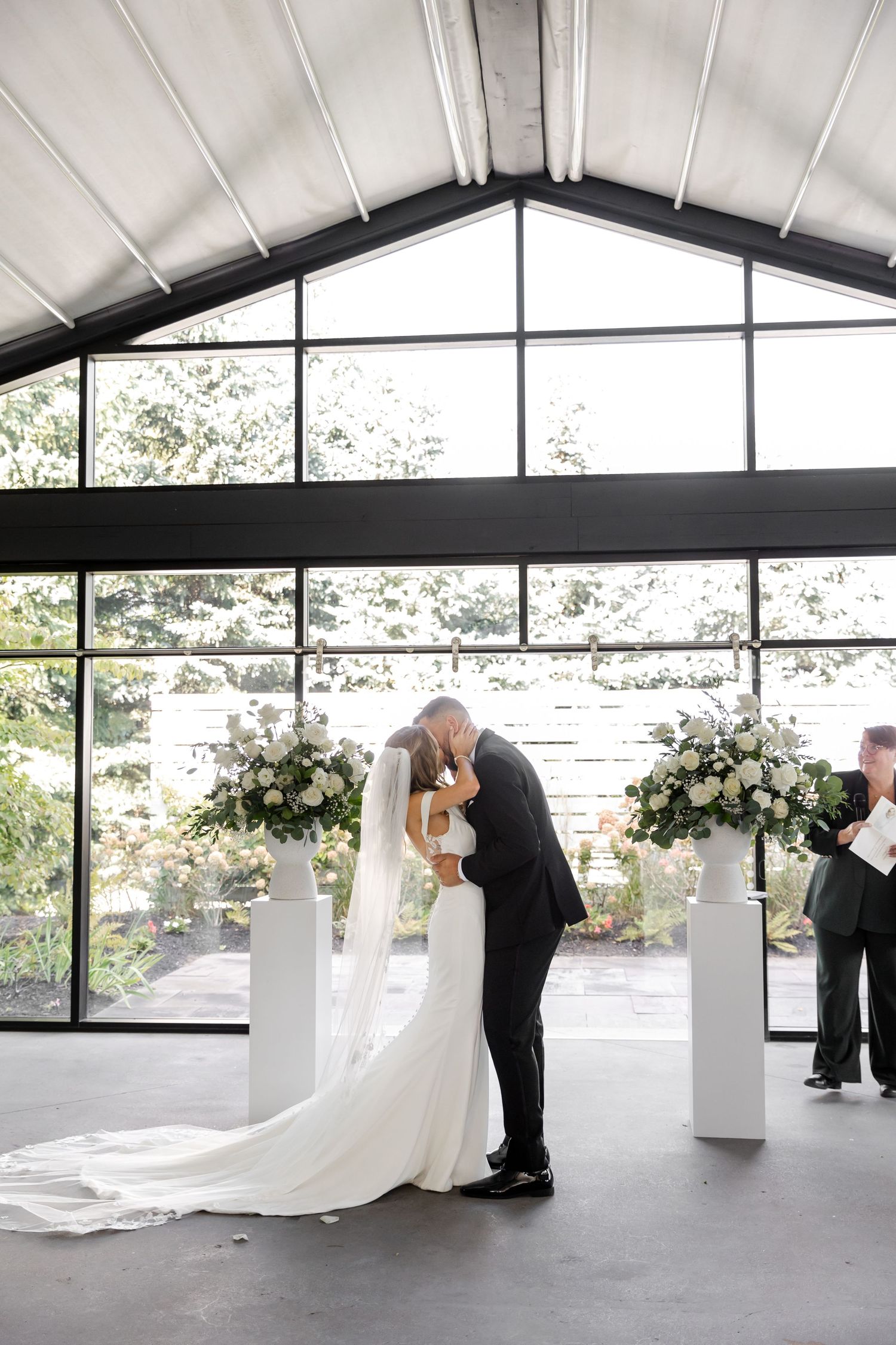 Wide view of elegant white wedding ceremony space with floral decorations.