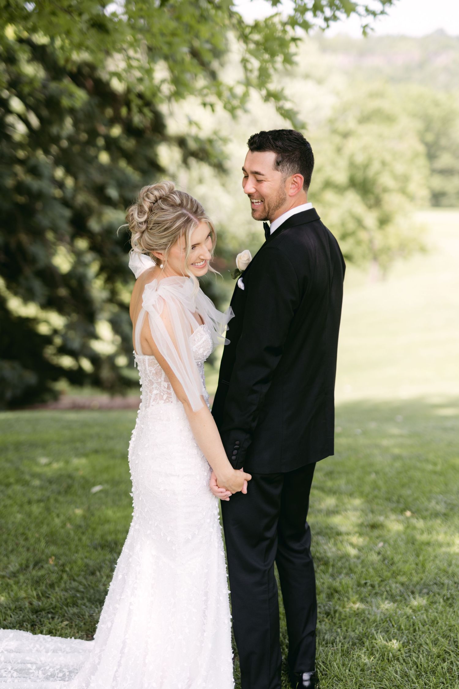 A romantic wedding portrait of a couple in formal attire standing together on a lush green lawn.