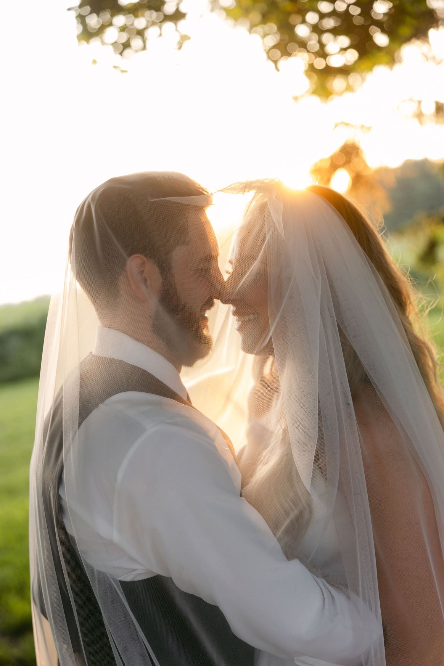 Romantic sunset wedding portraits with couple silhouetted against golden evening light.