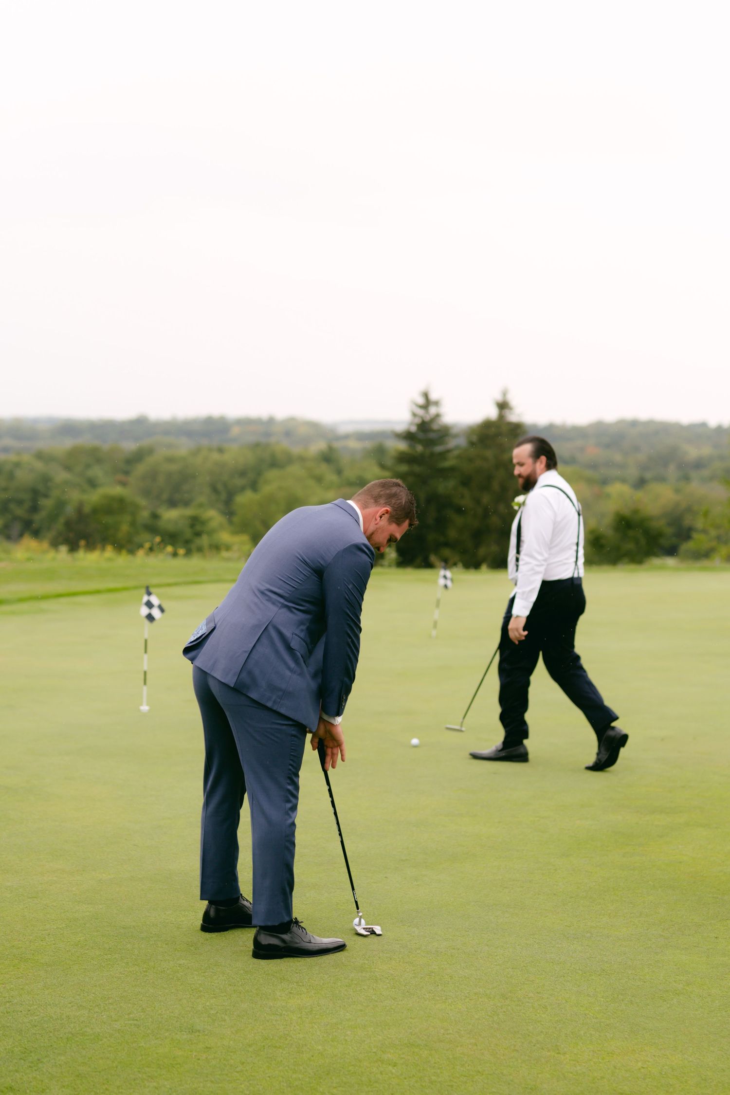 Groomsmen playing golf on a green course with clubs during wedding day festivities.