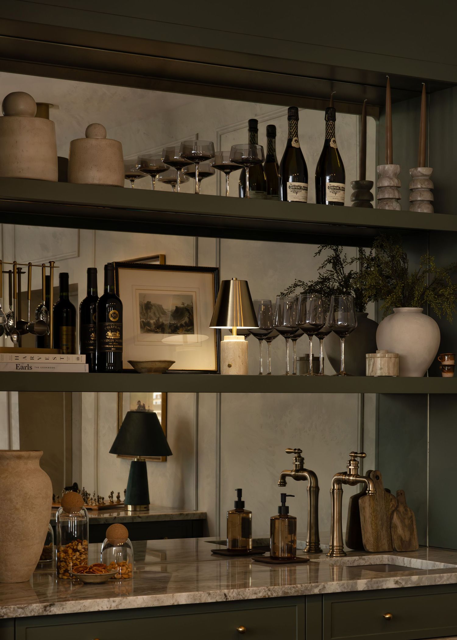 Luxurious bar setup with marble surfaces and dark wood shelving displaying bottles and barware.