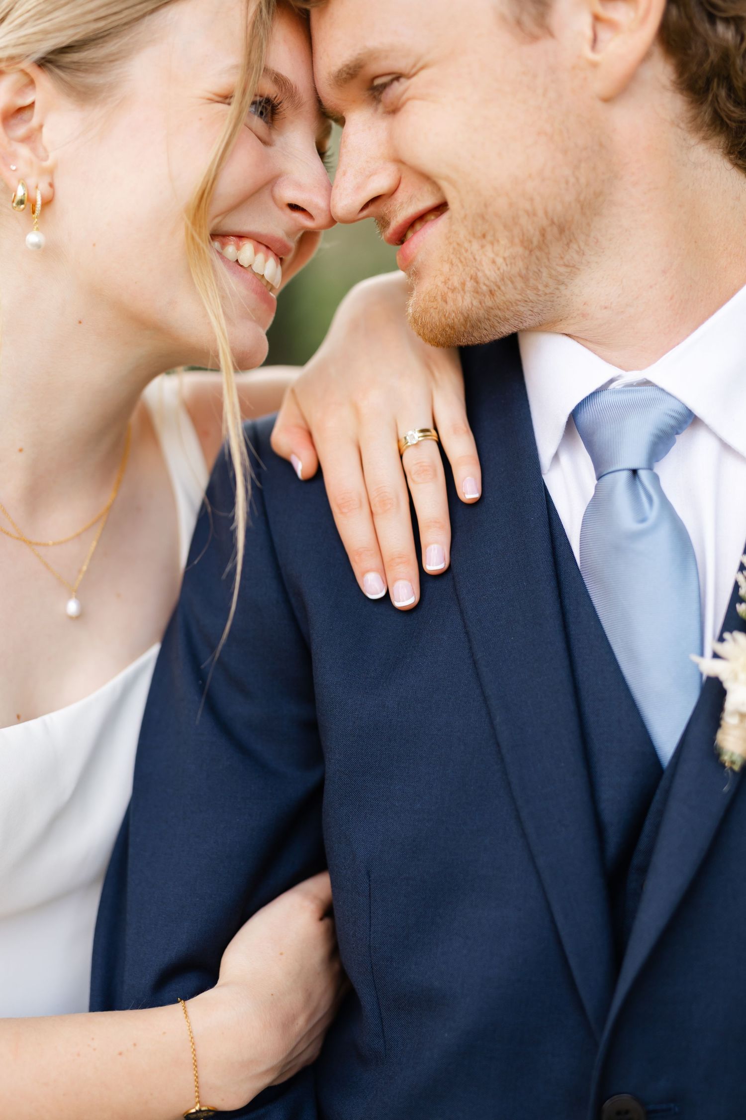 Close-up of newlyweds sharing intimate moment showing wedding ring detail.