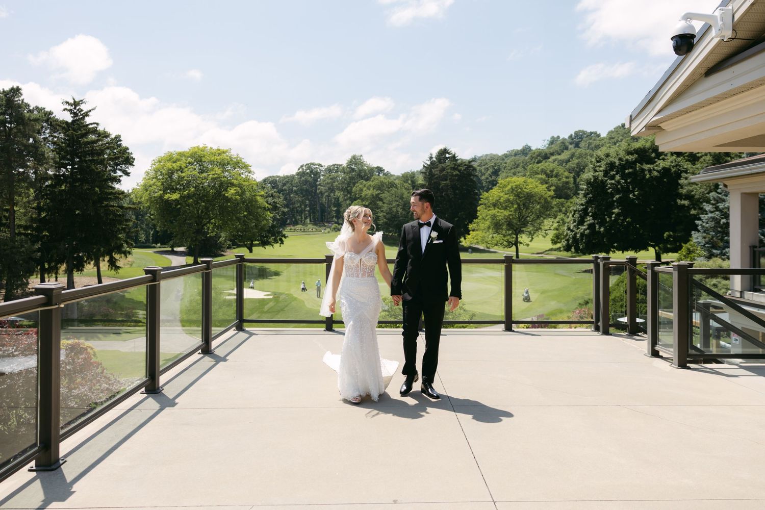 Wide shot of terrace overlooking golf course with couple in formal attire.