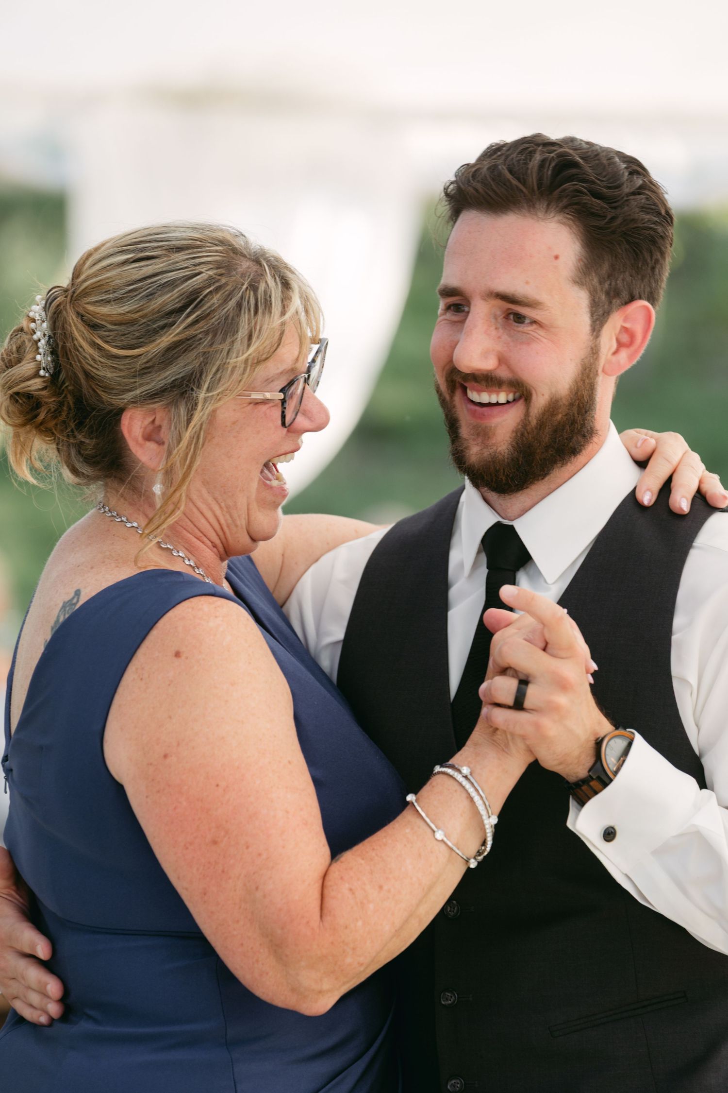 Candid sequence shows joyful interaction between wedding couple in navy and black formal attire.