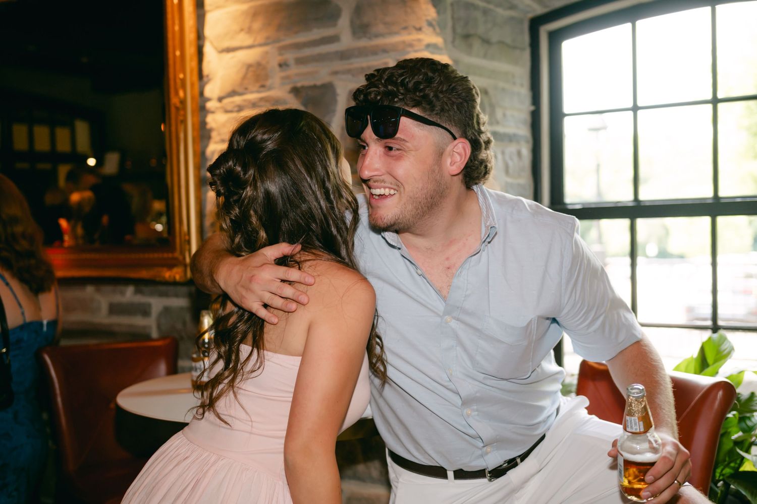Dancing guests enjoying celebration at rustic indoor wedding reception.