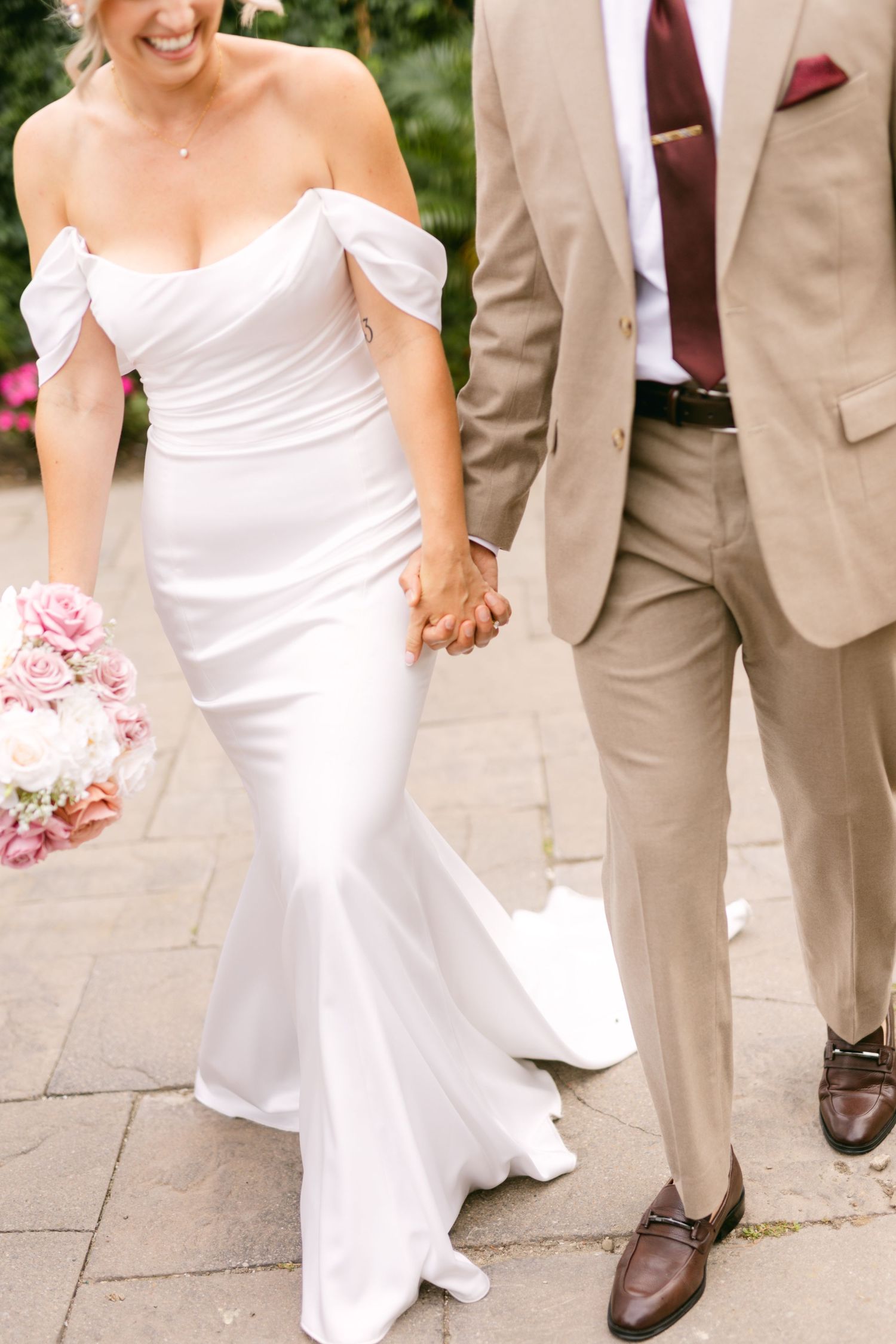 Wedding couple walking together on stone pavement with flowing white dress and tan suit.