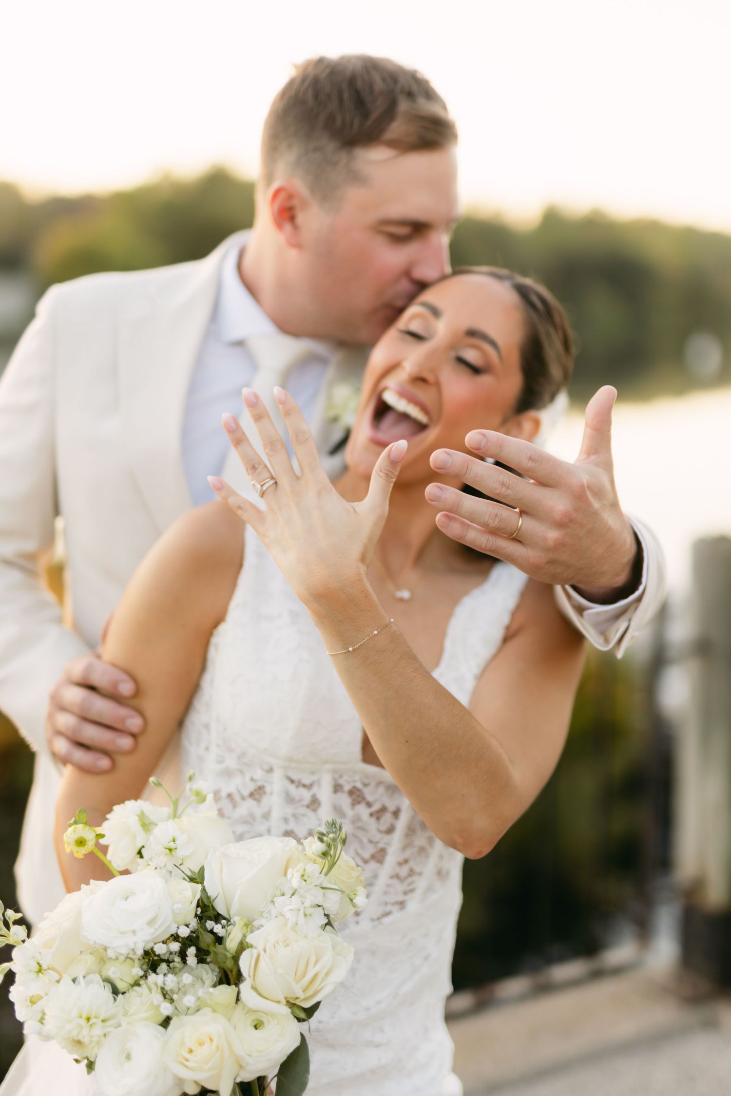 Romantic wedding couple sharing an intimate moment with white bouquet at sunset.