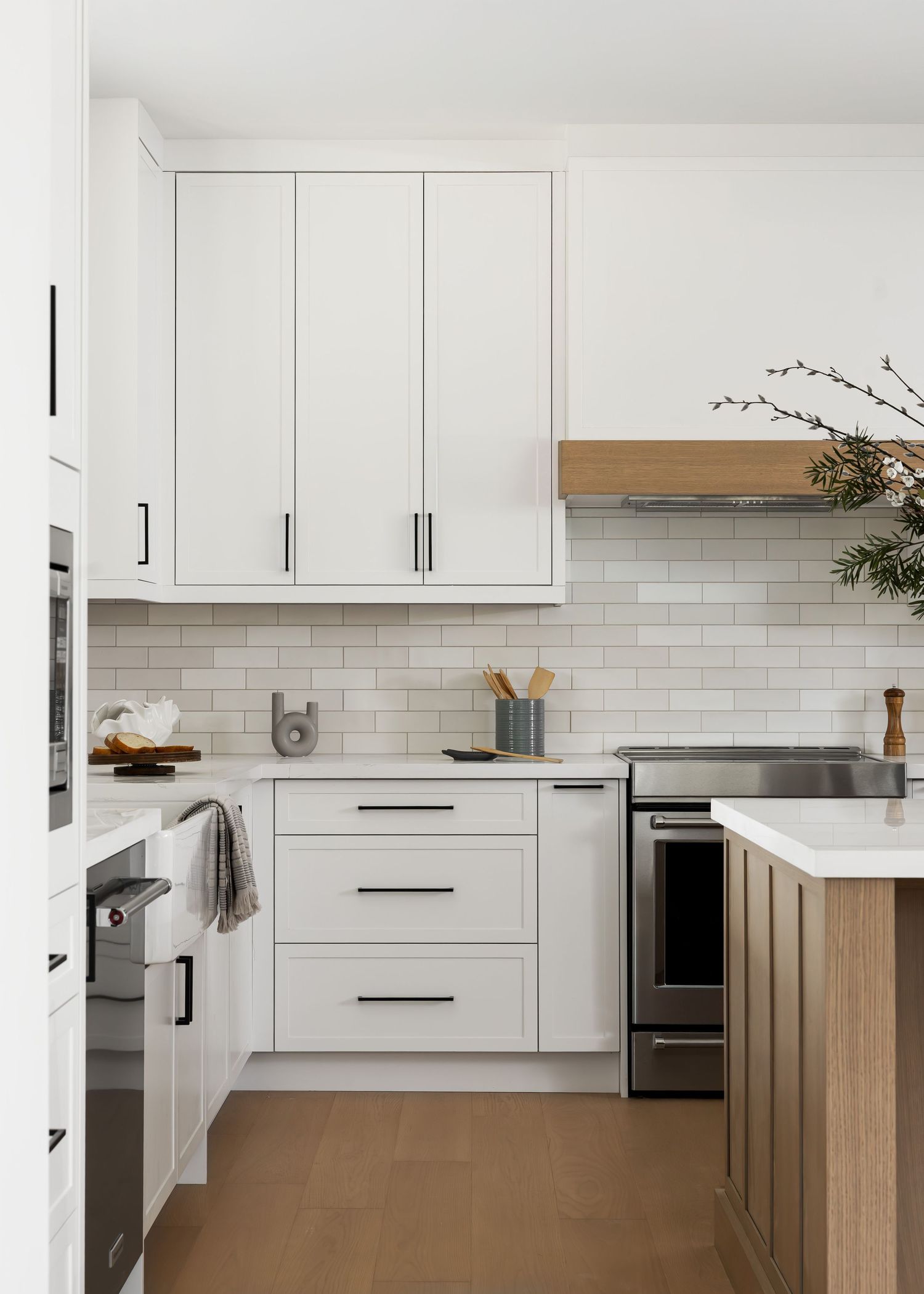 White kitchen with wood accents featuring modern cabinetry and subway tile backsplash.