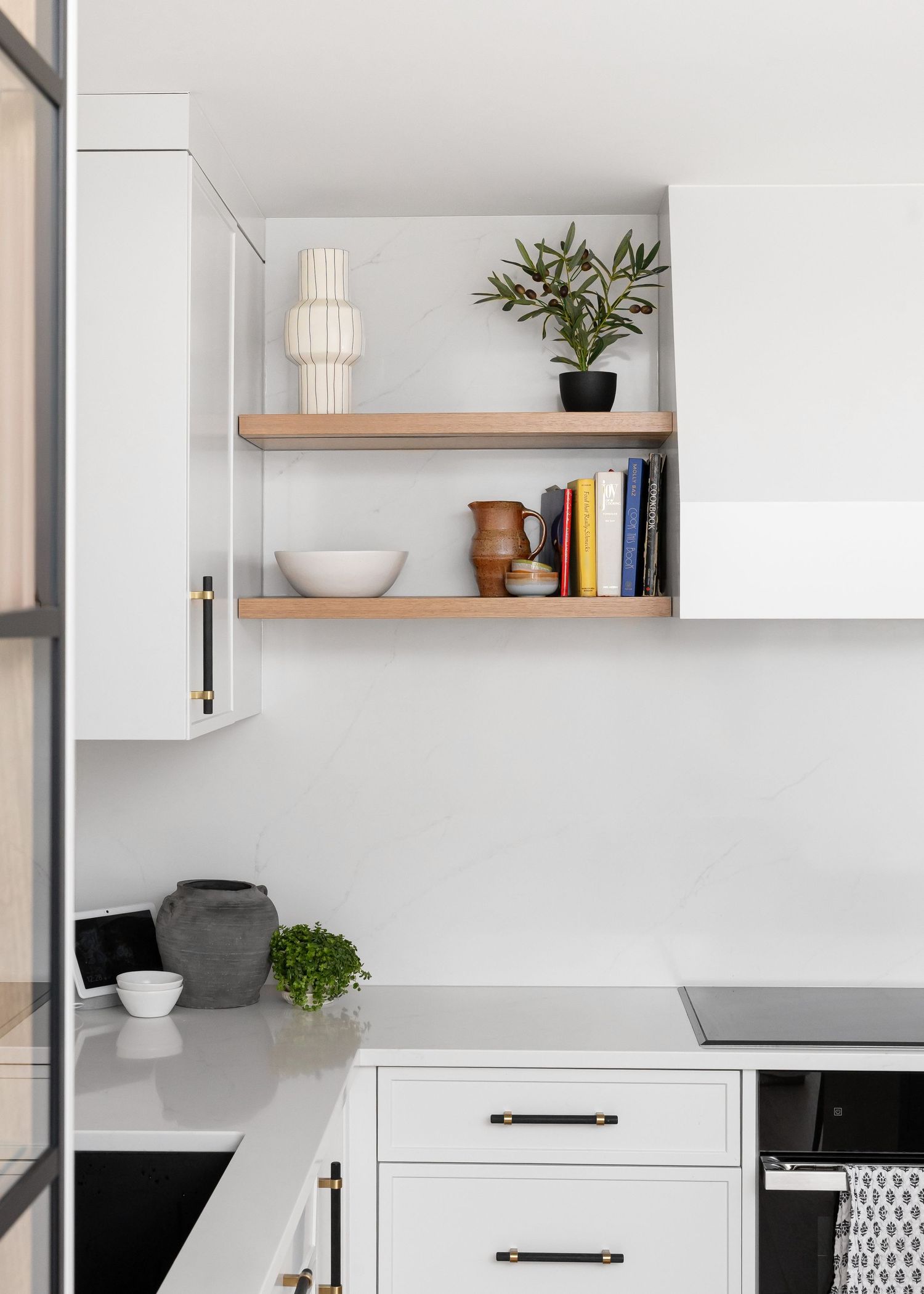 Modern built-in shelving with decorative items and white cabinetry in kitchen corner.