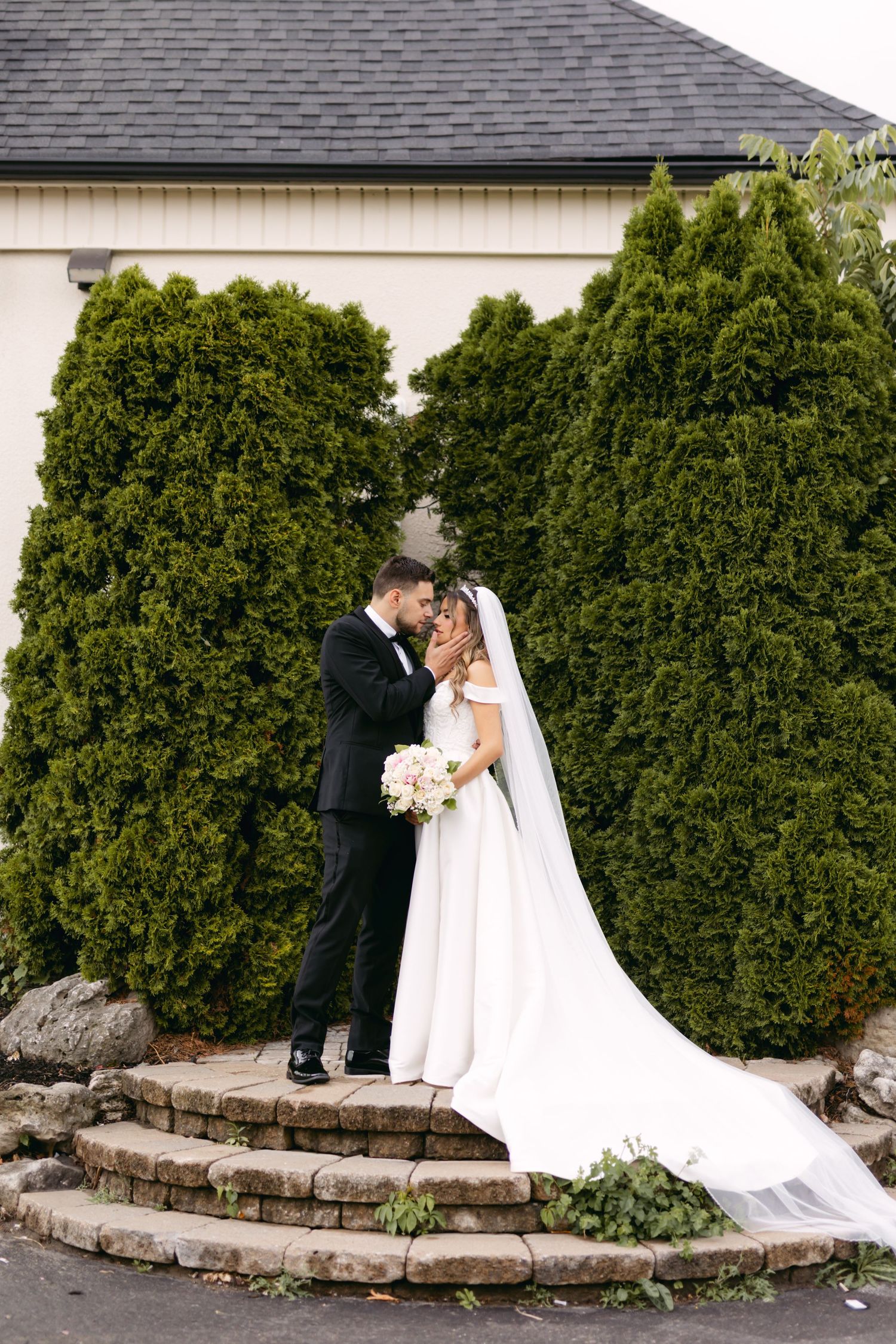 Romantic wedding portraits captured against manicured garden backdrop.
