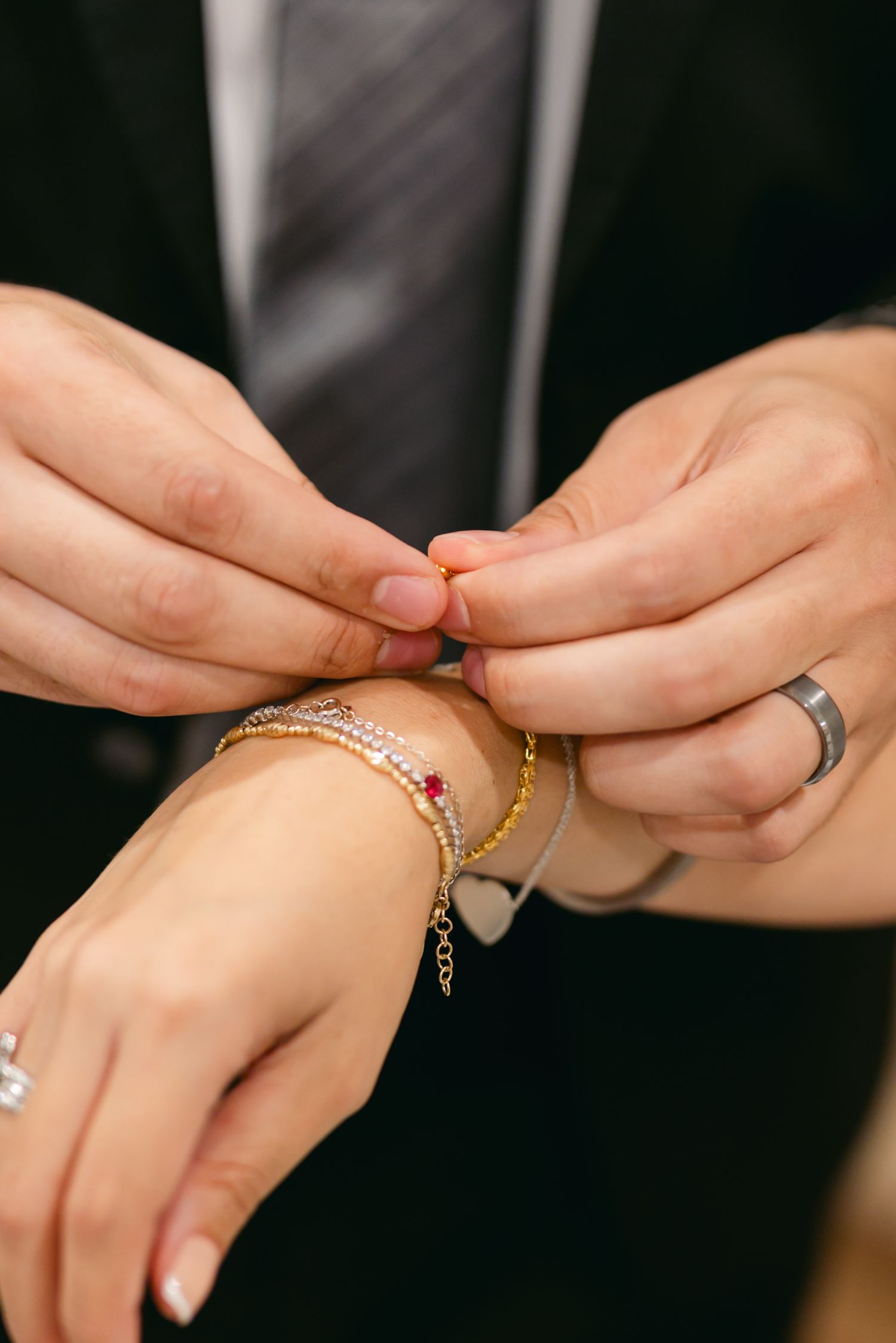 Close-up of hands fastening a delicate gold bracelet around a wrist.