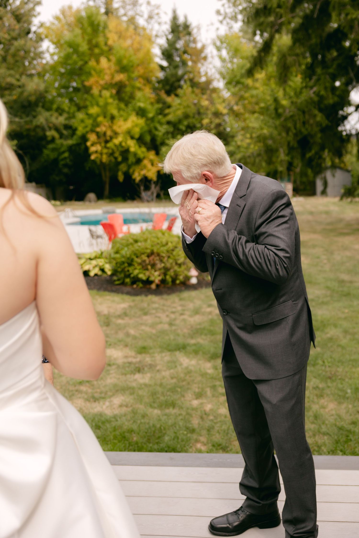 An emotional moment captured during a first look as someone wipes away tears on an outdoor deck.
