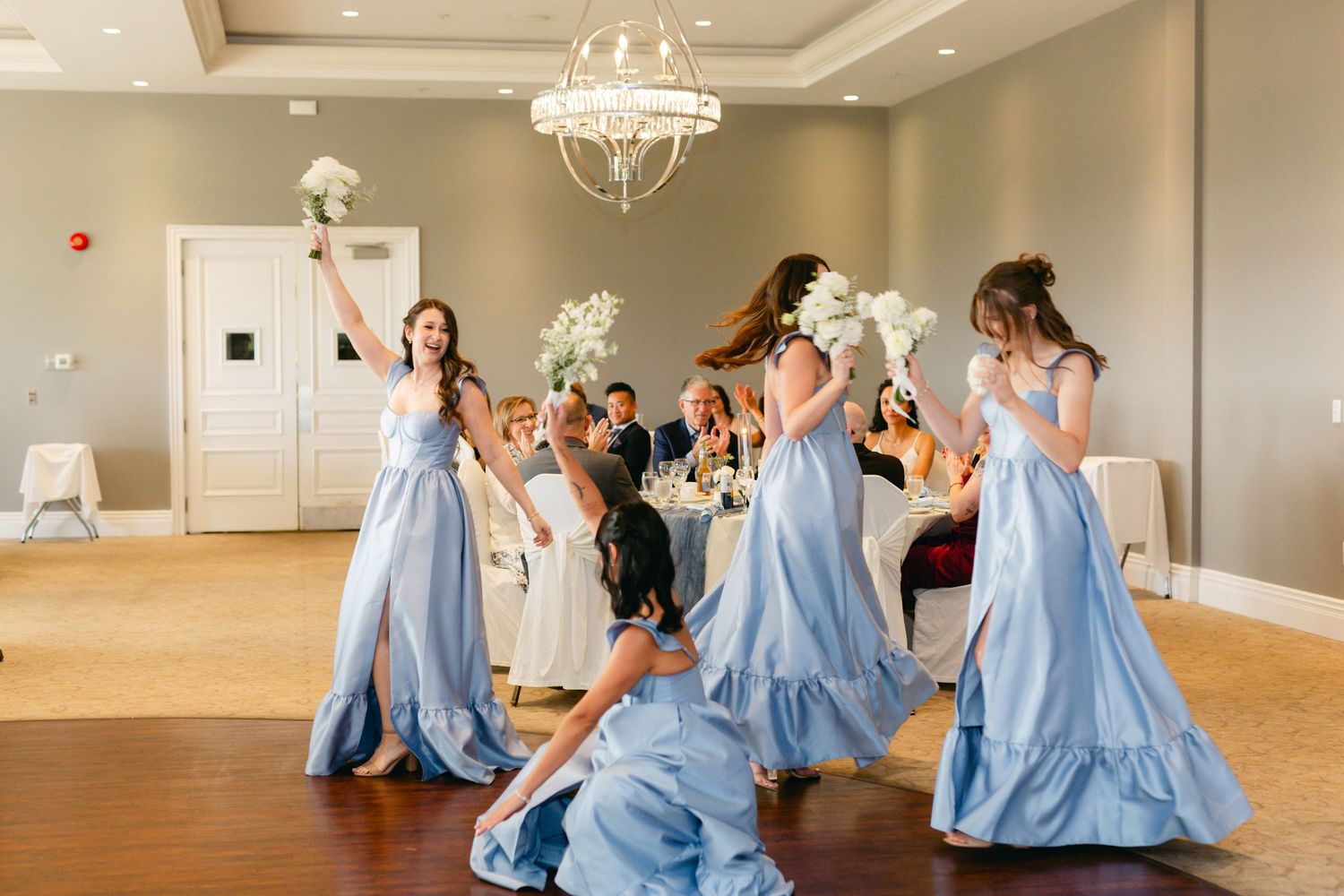Wedding party dancing in coordinated routine with bridesmaids in powder blue dresses.