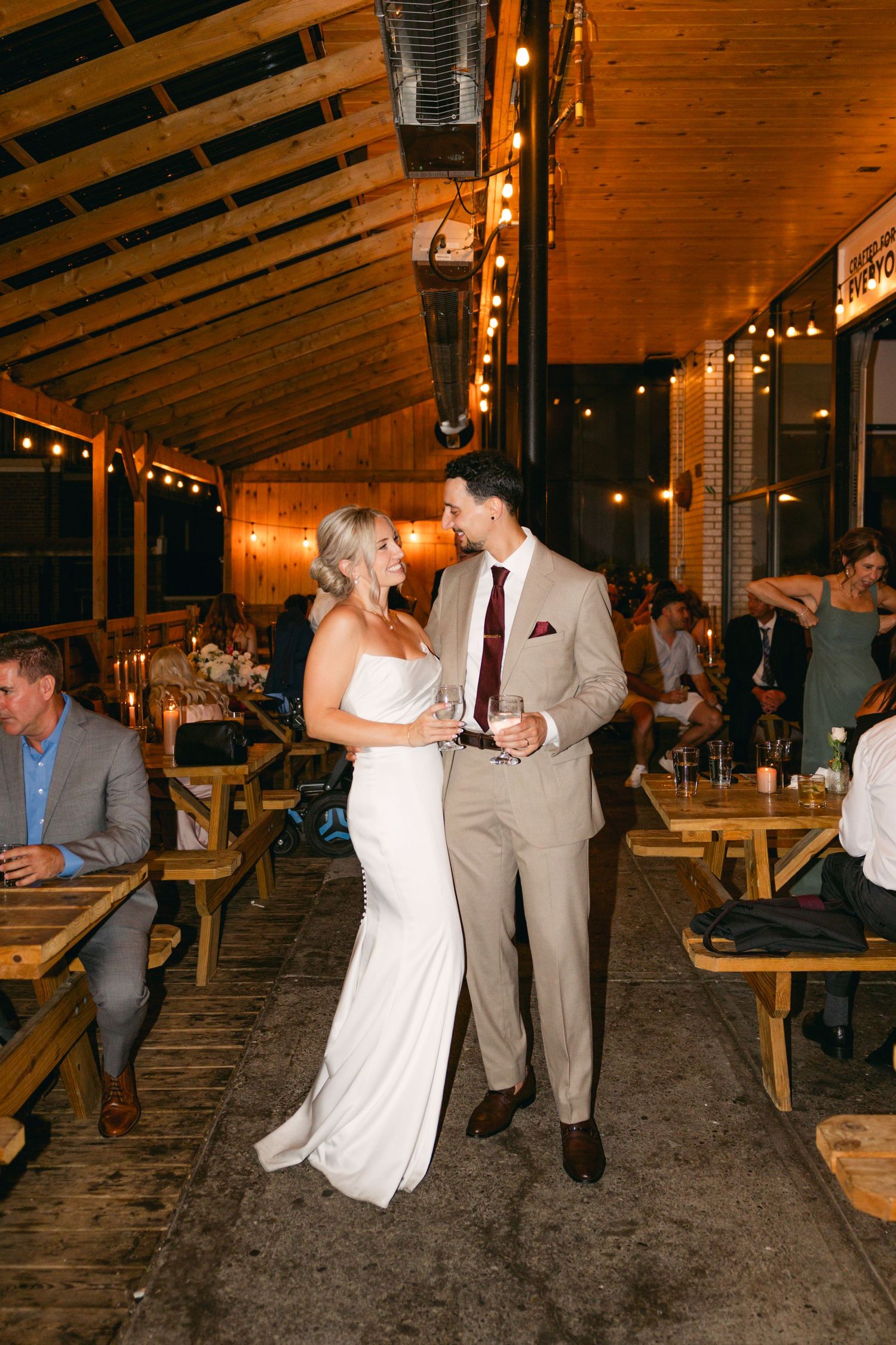 Wedding celebration in rustic wooden venue with string lights overhead.