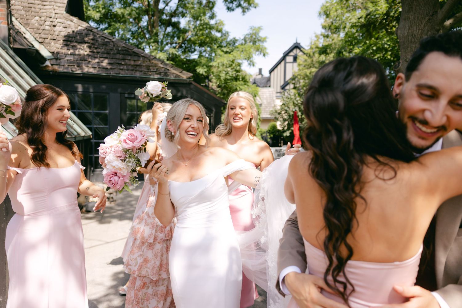 Bridesmaids in pink dresses celebrate during wedding festivities outdoors.