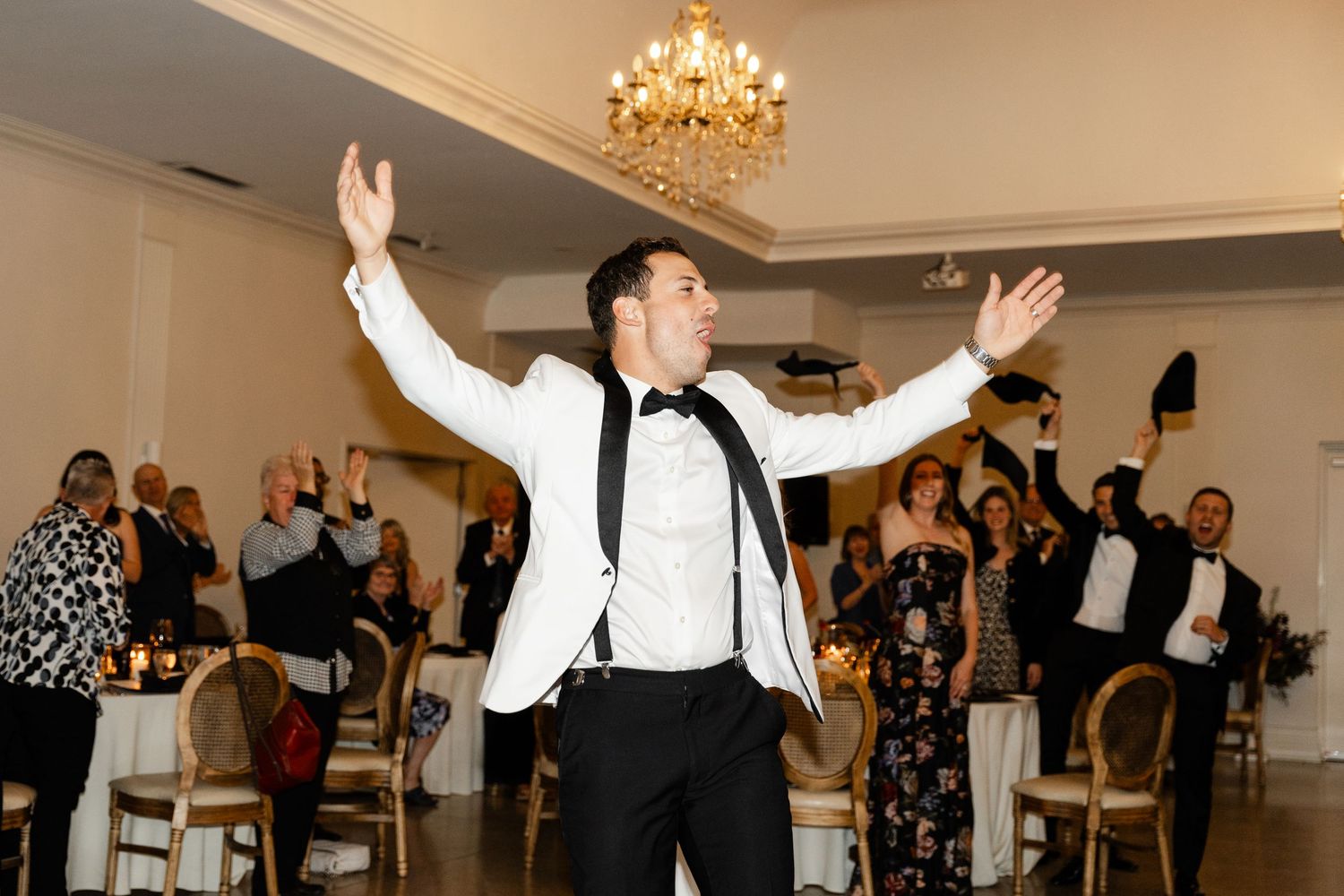 Wedding reception dance floor with guests celebrating under crystal chandeliers.