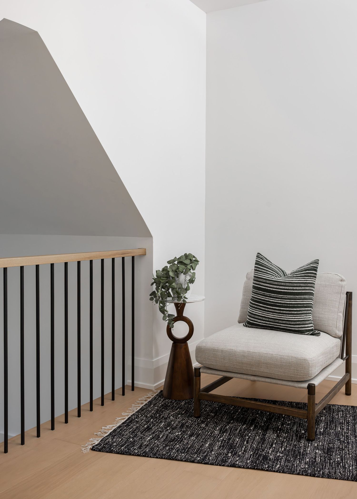 Modern staircase landing with black railing, wooden bench seating, and minimalist decor on dark area rug.