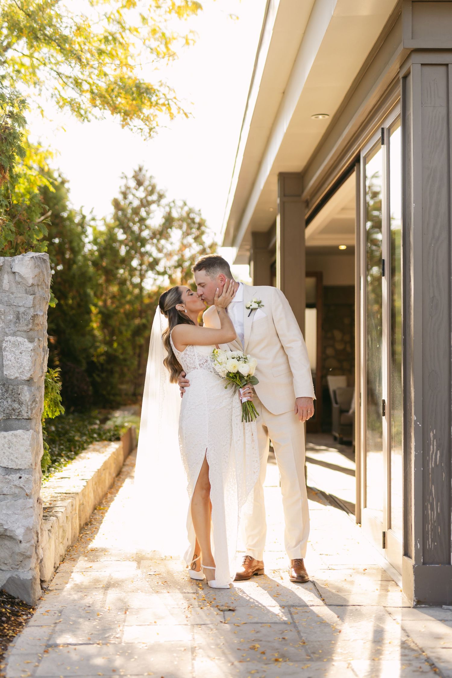 Romantic wedding portraits in a sunlit corridor with stone and glass architectural elements.
