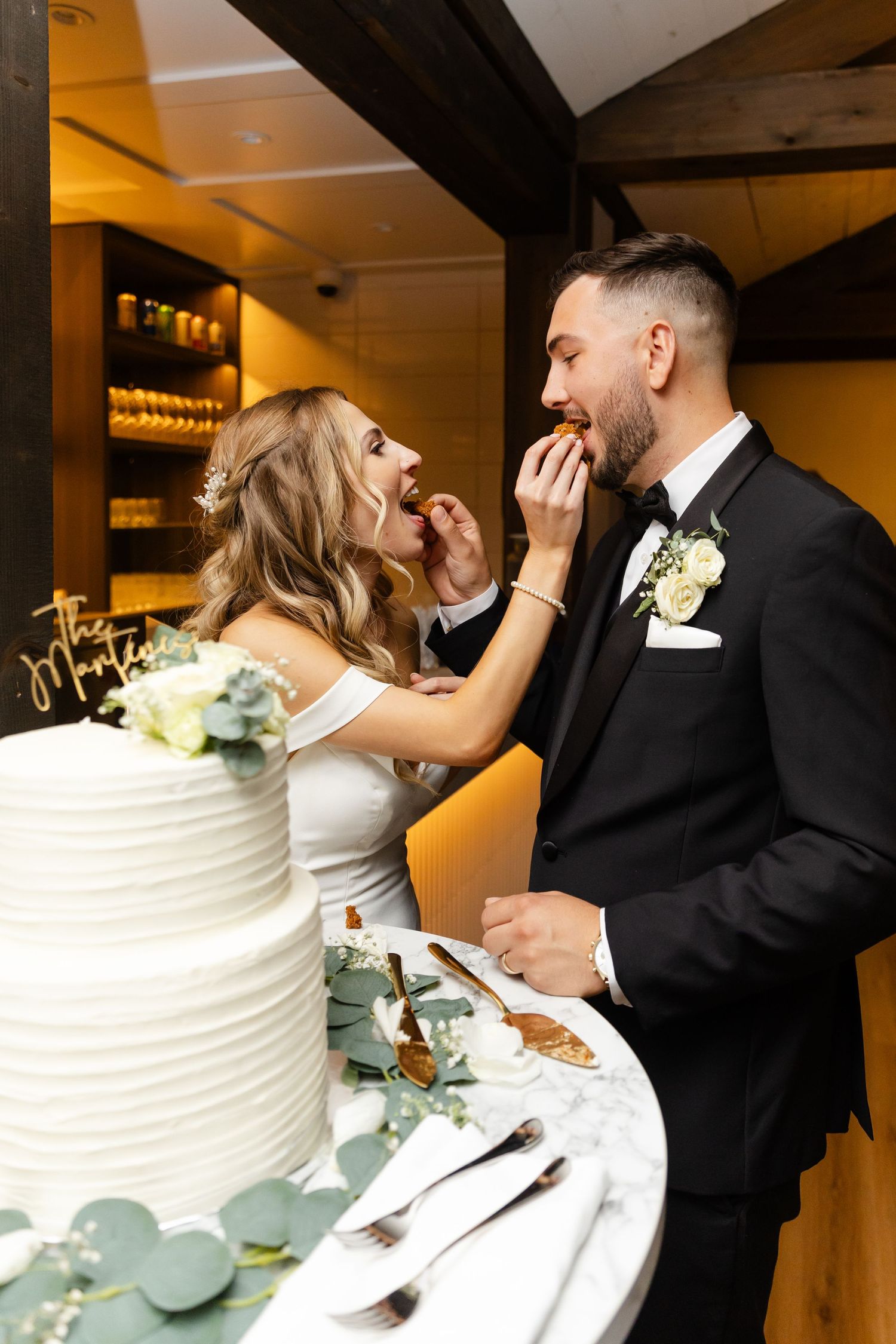 Wedding couple sharing cake and laughter during their reception celebration.