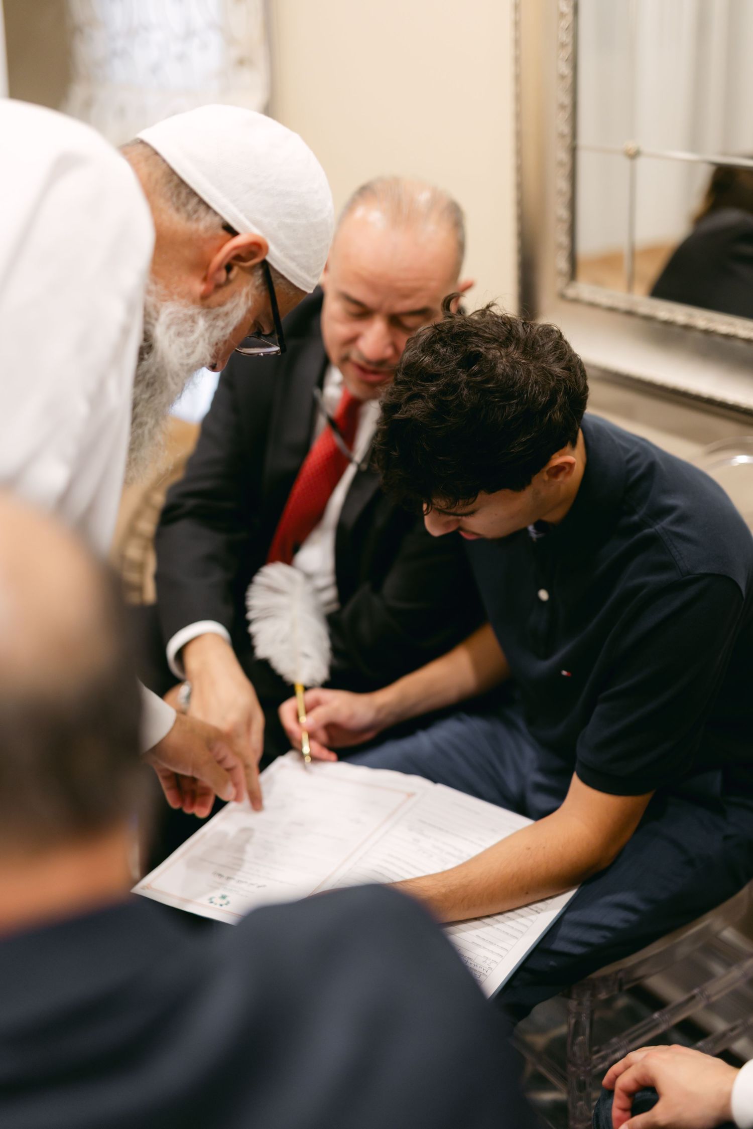People signing documents at a table during what appears to be a formal ceremony or meeting.