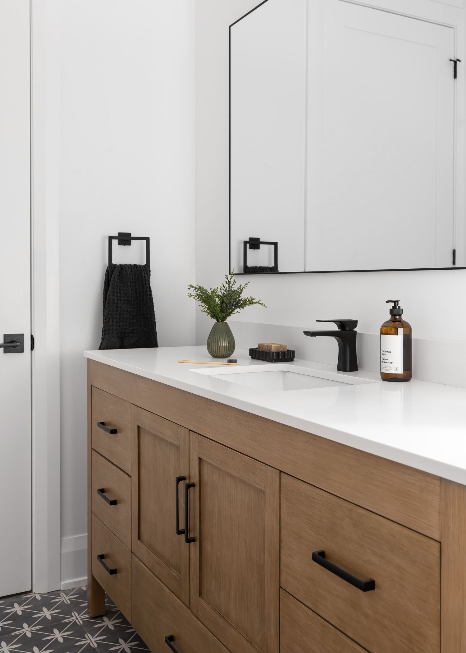 Modern bathroom vanity with wood cabinets, white countertops, and black hardware offers sleek storage solutions.