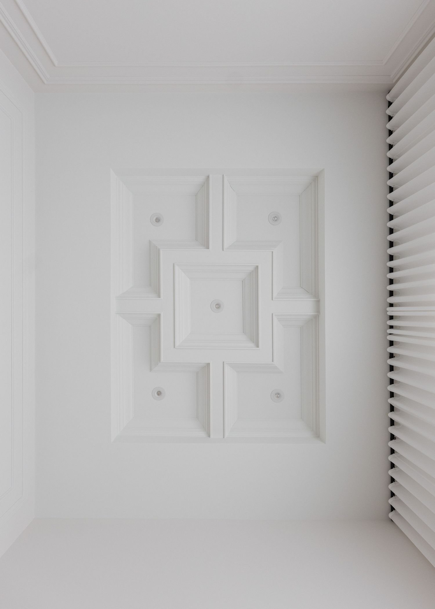 White ceiling detail with geometric patterns and recessed lighting.