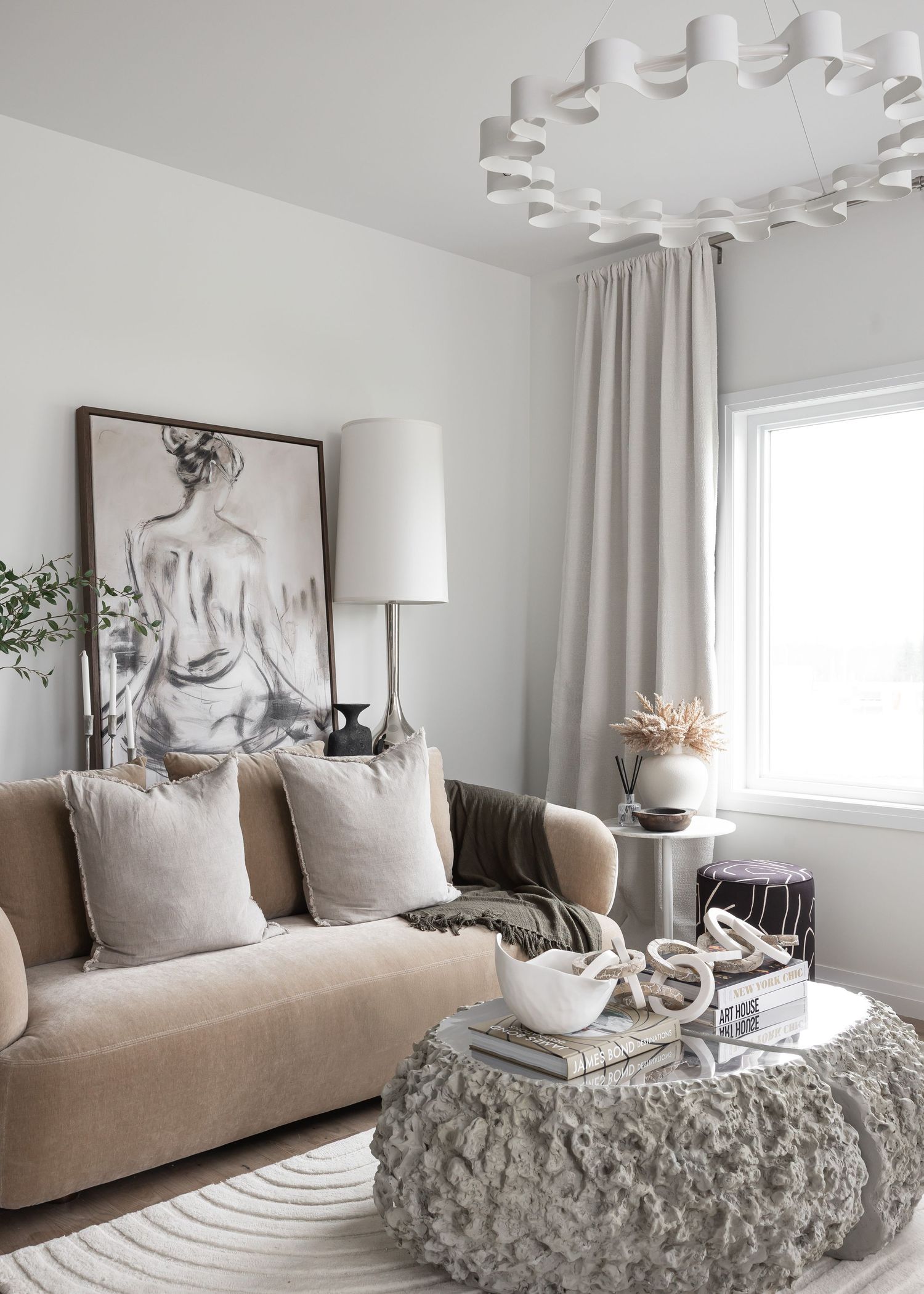Modern living room with beige sofa, abstract art, and unique ceiling light fixture.