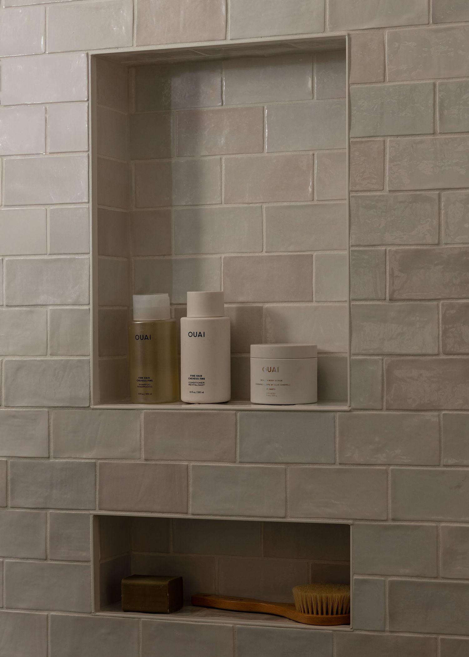 Modern bathroom wall with built-in storage niches showcasing minimalist toiletries and accessories.