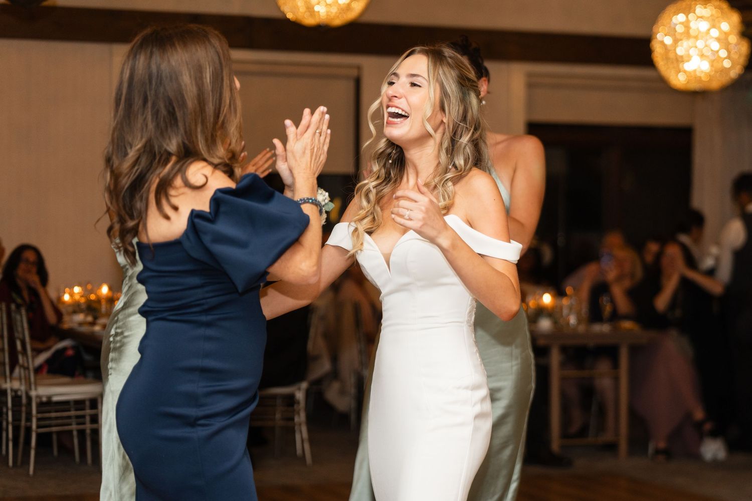 Wedding celebration with guests dancing and enjoying festivities under warm lighting.