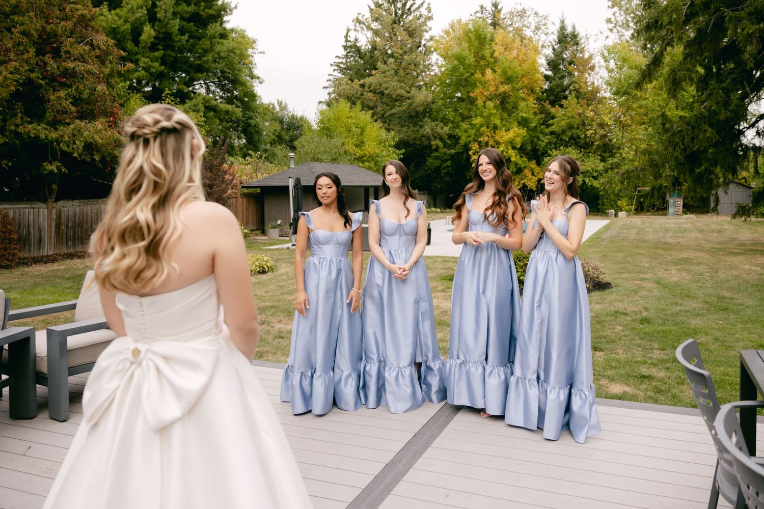 Wedding party in light blue dresses and white gown pose outdoors on an autumn day.