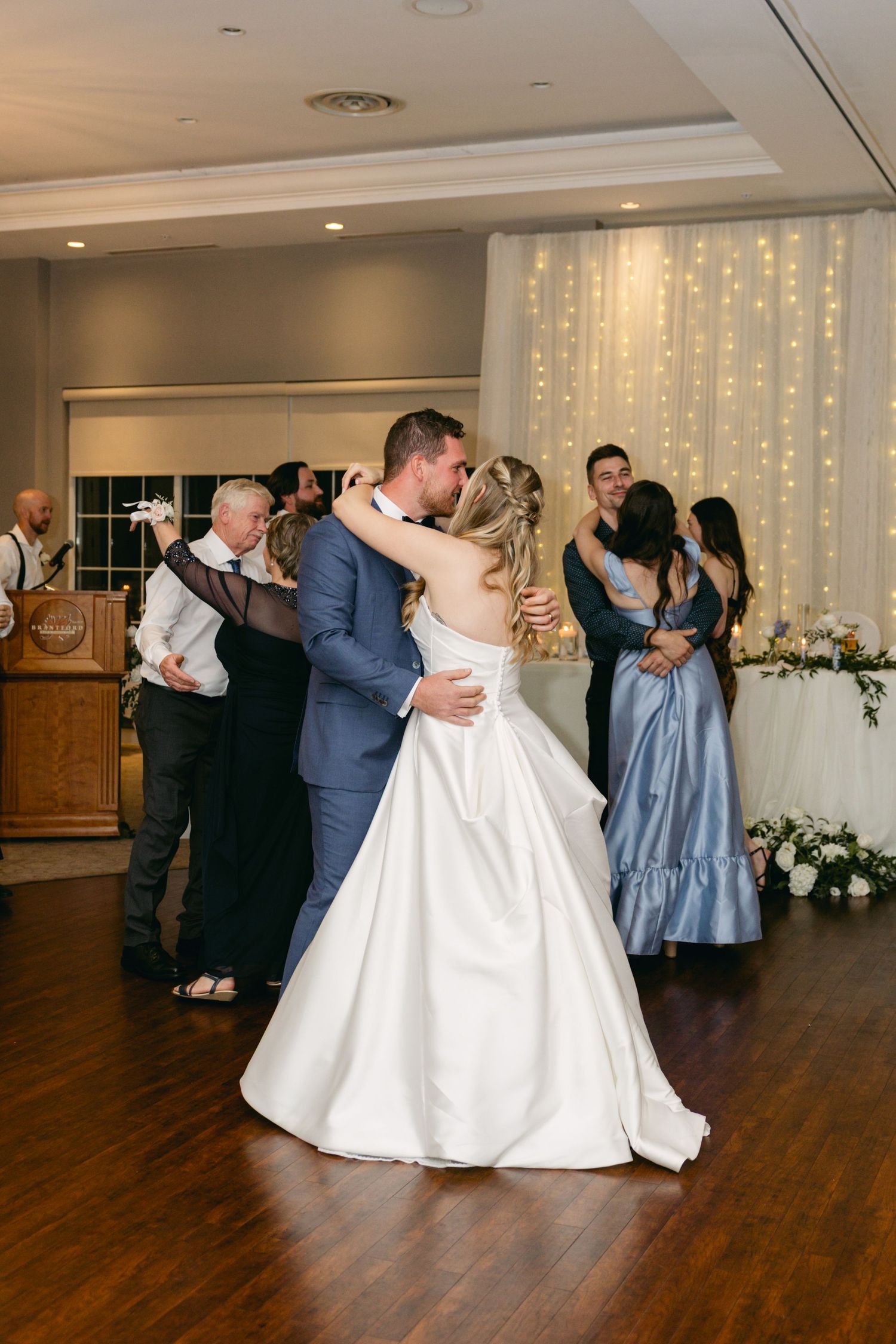 Wedding party dancing in celebration with mix of white and blue formal attire.