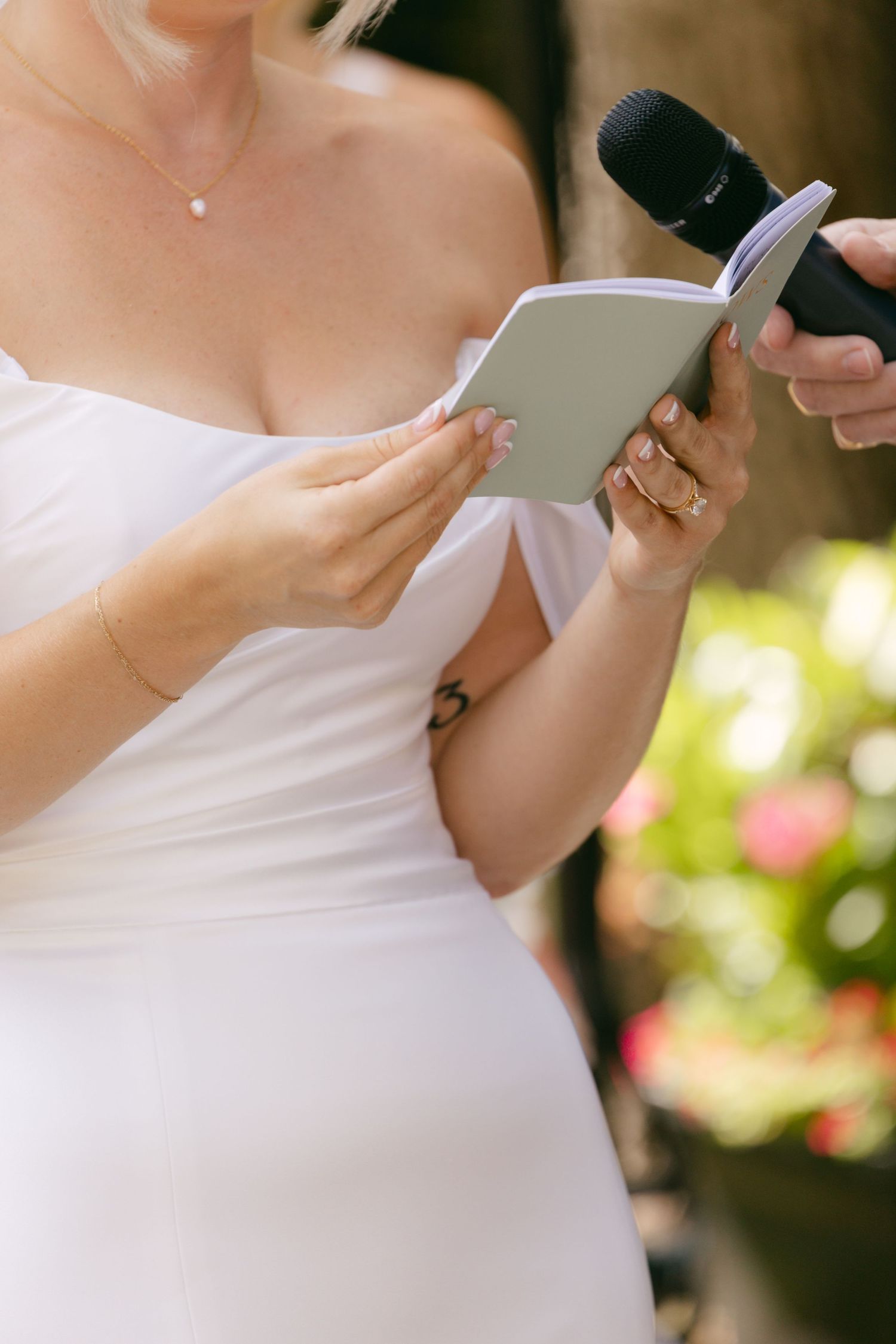 Close-up details of a bride holding a phone during wedding preparations outdoors.