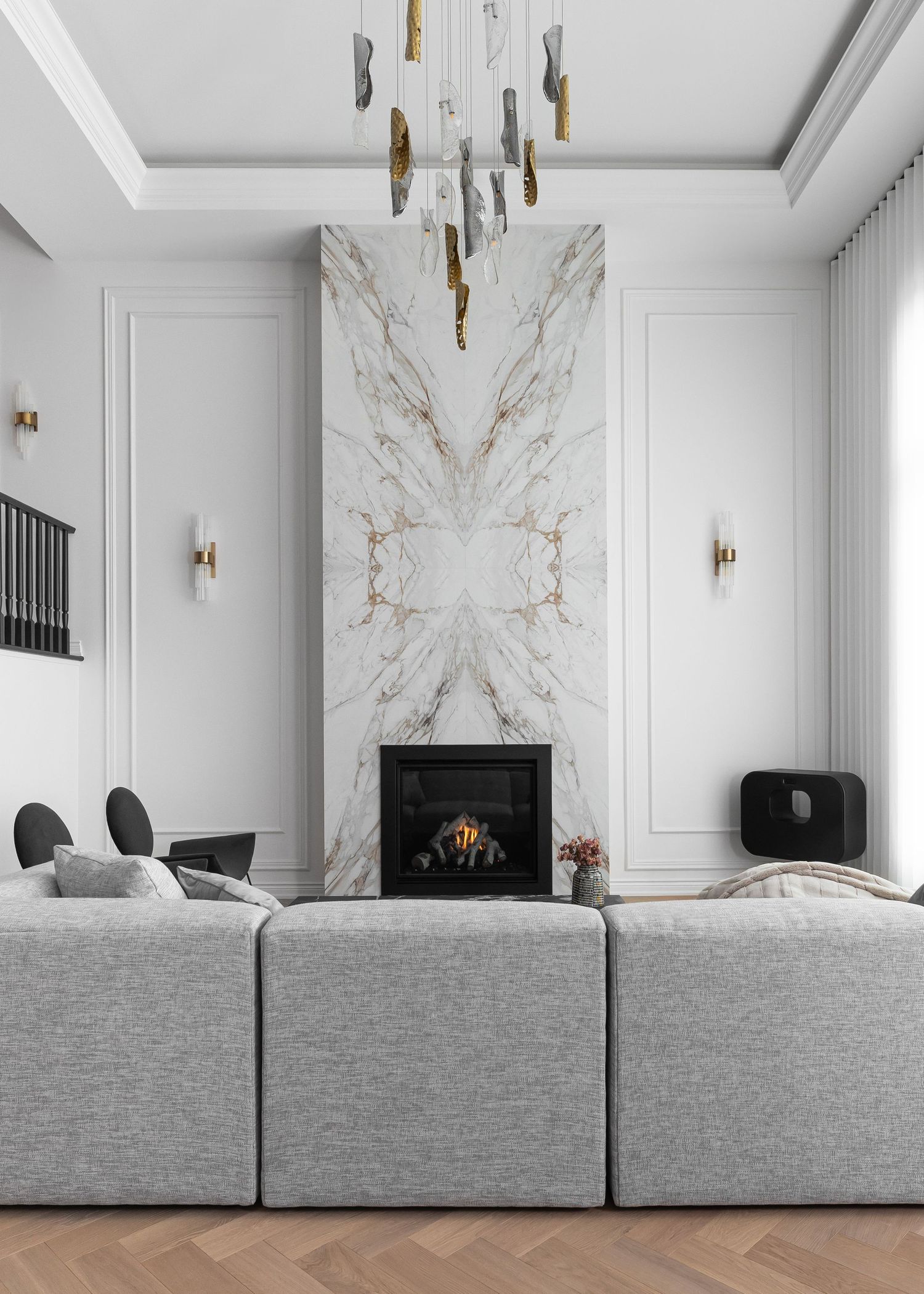 Living space featuring marble accent wall, modern fireplace, and plush grey sectional sofa.